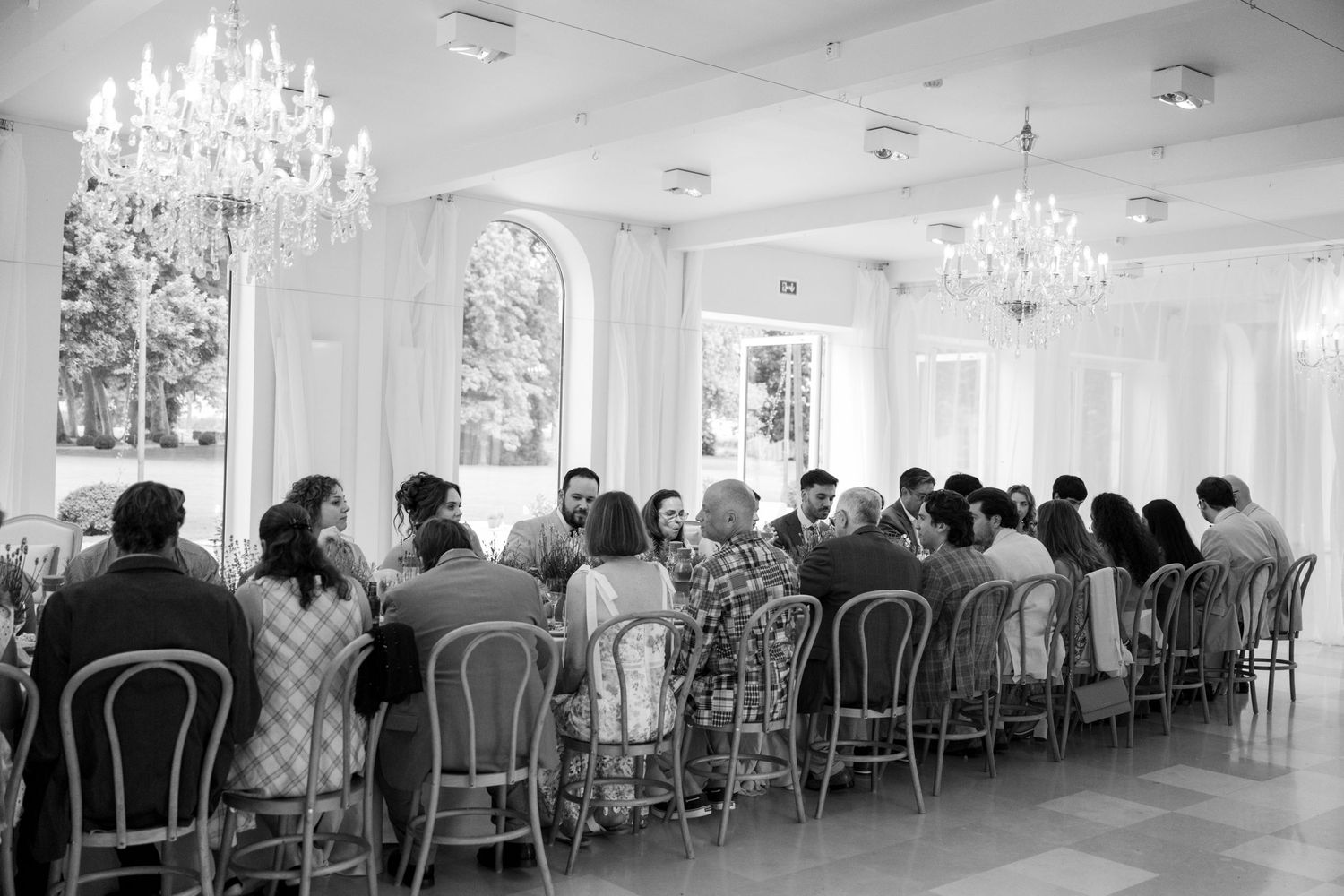 Elegant white banquet hall with crystal chandeliers and rows of chairs arranged for a formal event.
