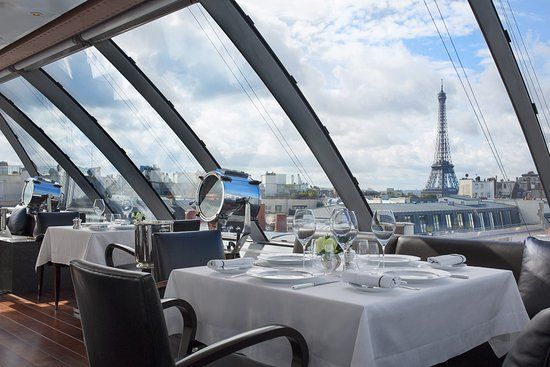 Elegant restaurant interior with glass ceiling and panoramic views of the Eiffel Tower.