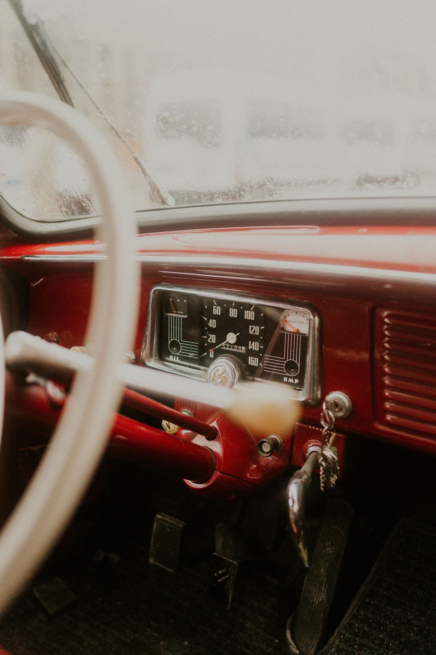 Interior view of a classic car dashboard showing vintage gauges and red upholstery.