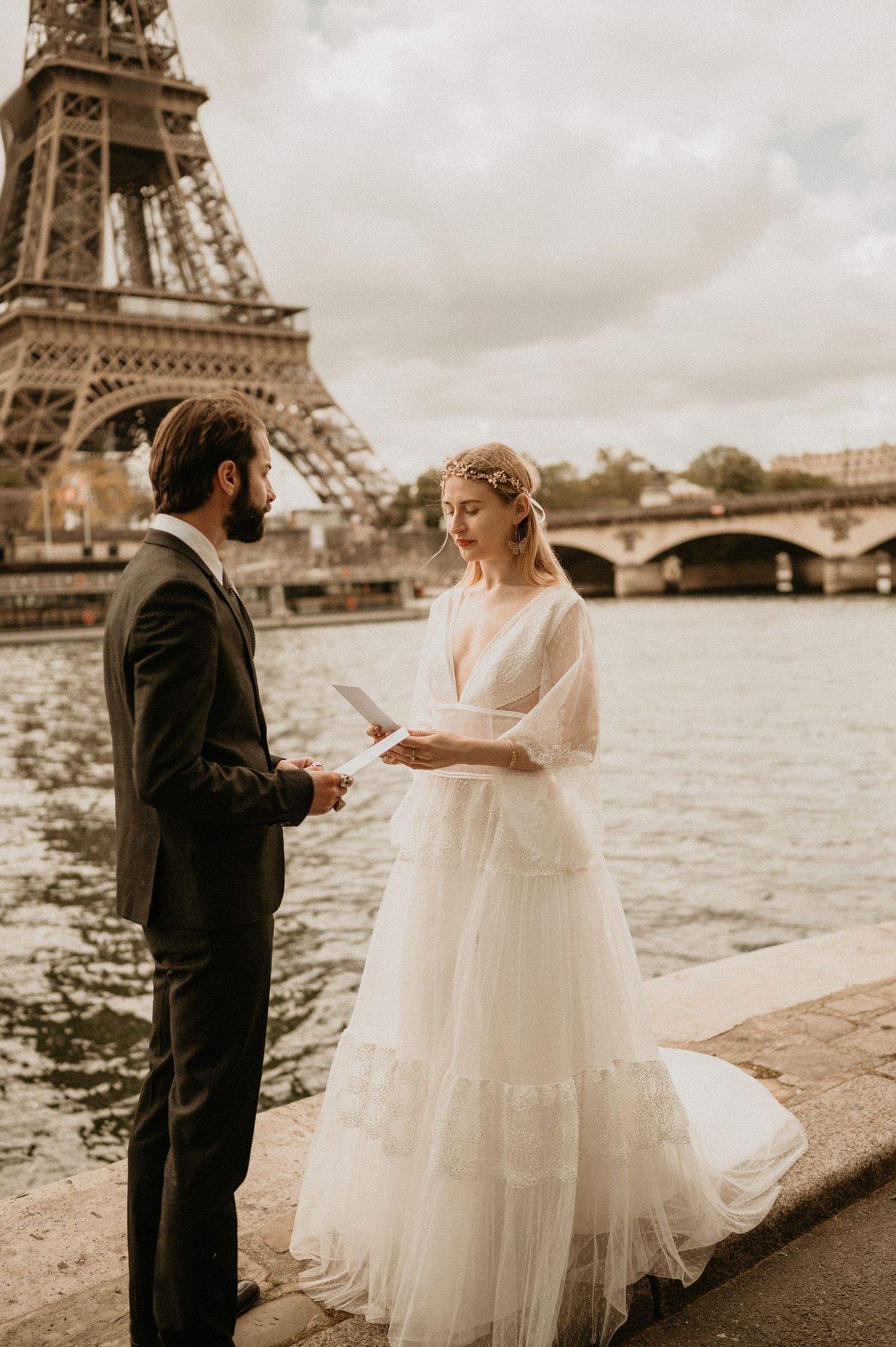 Couple exchanging vows by Seine River with Eiffel Tower backdrop in Paris.