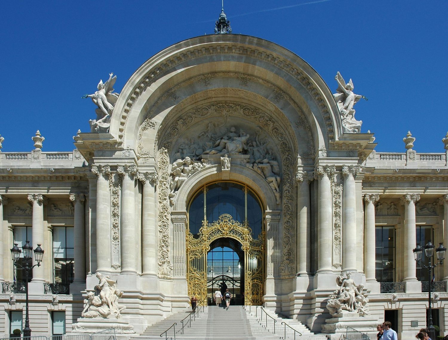 Ornate Beaux-Arts entrance of the Petit Palais museum in Paris with classical sculptures.