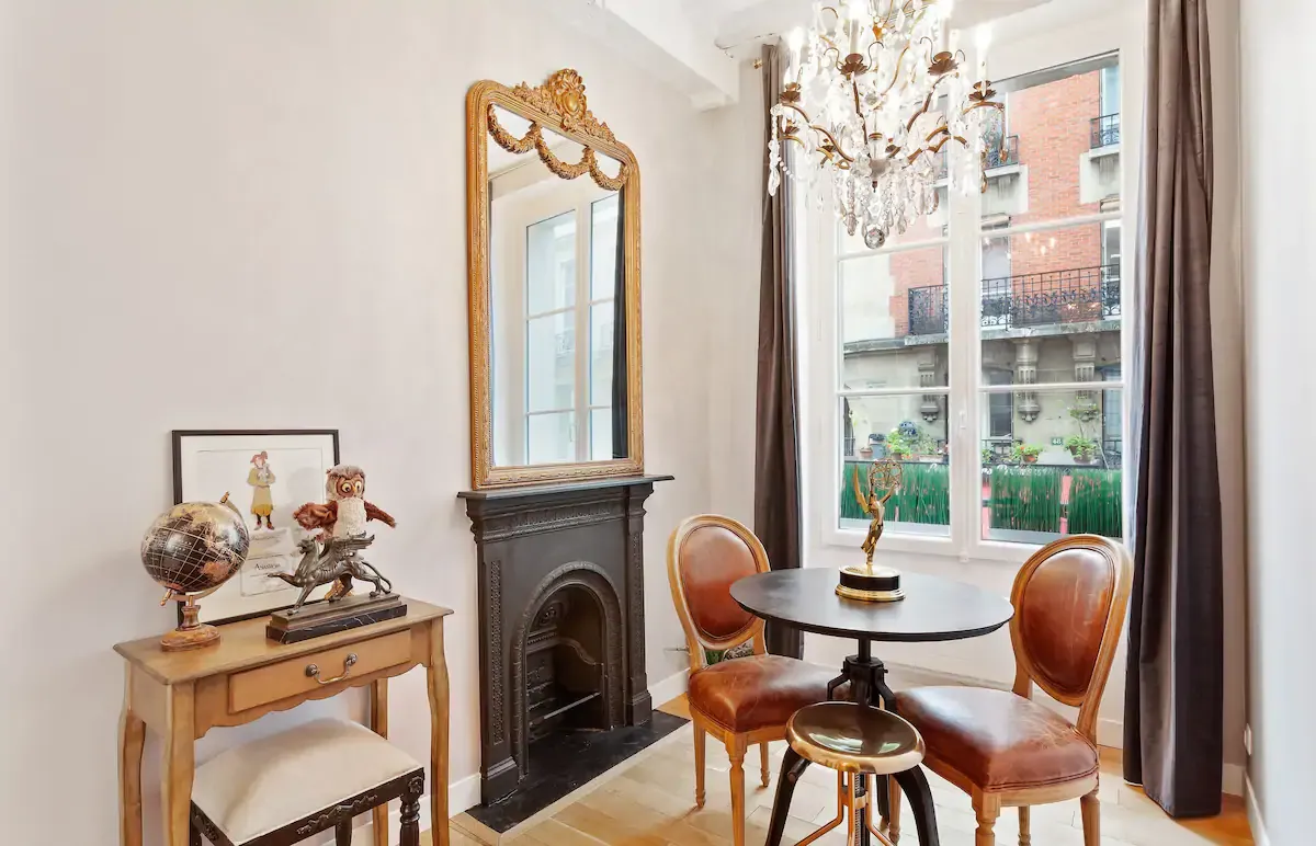 Elegant sitting area with vintage mirror, copper chairs and bay window in classic Parisian apartment.