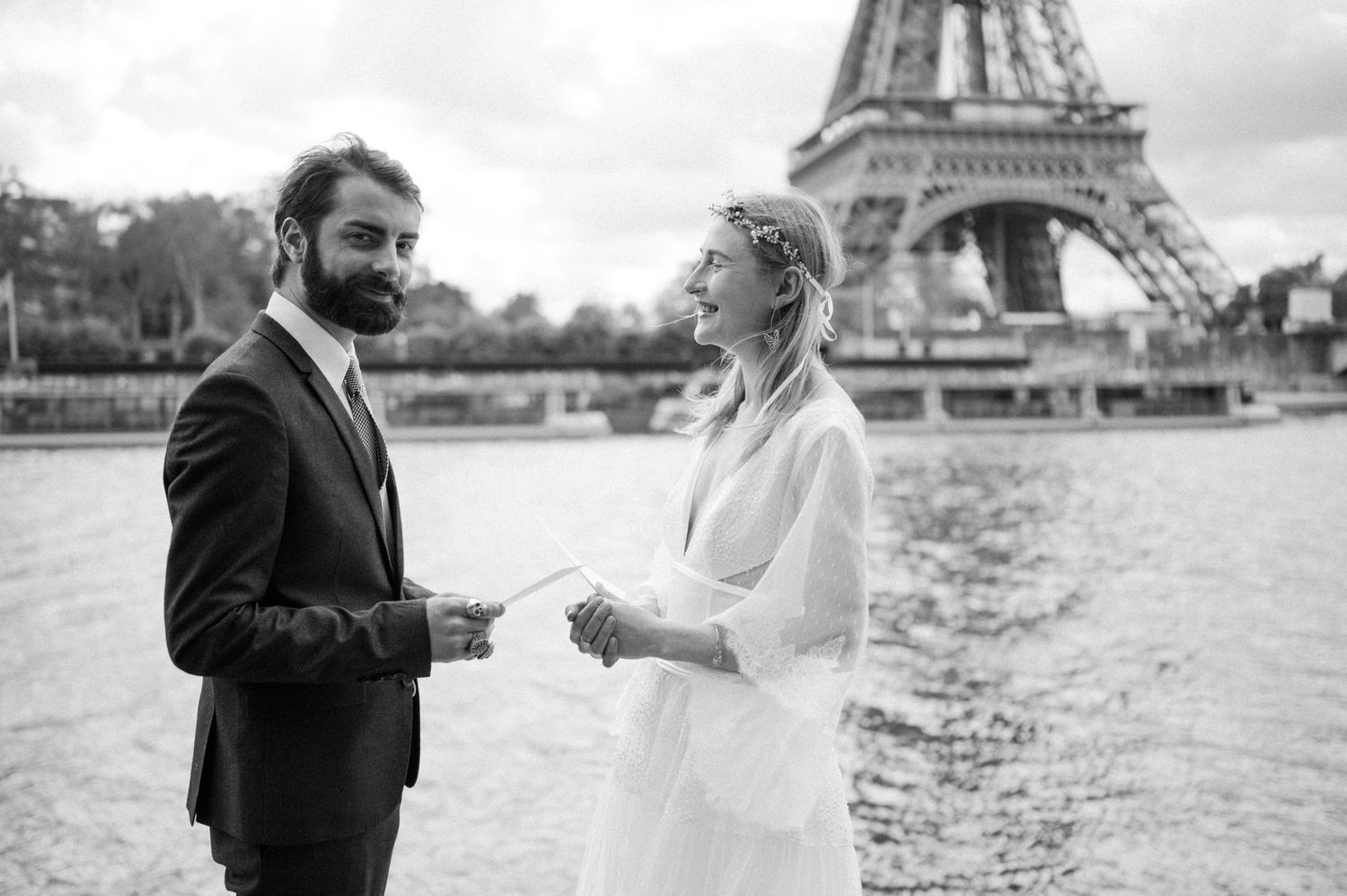 Wedding couple exchanging rings by the Seine River with Eiffel Tower backdrop.