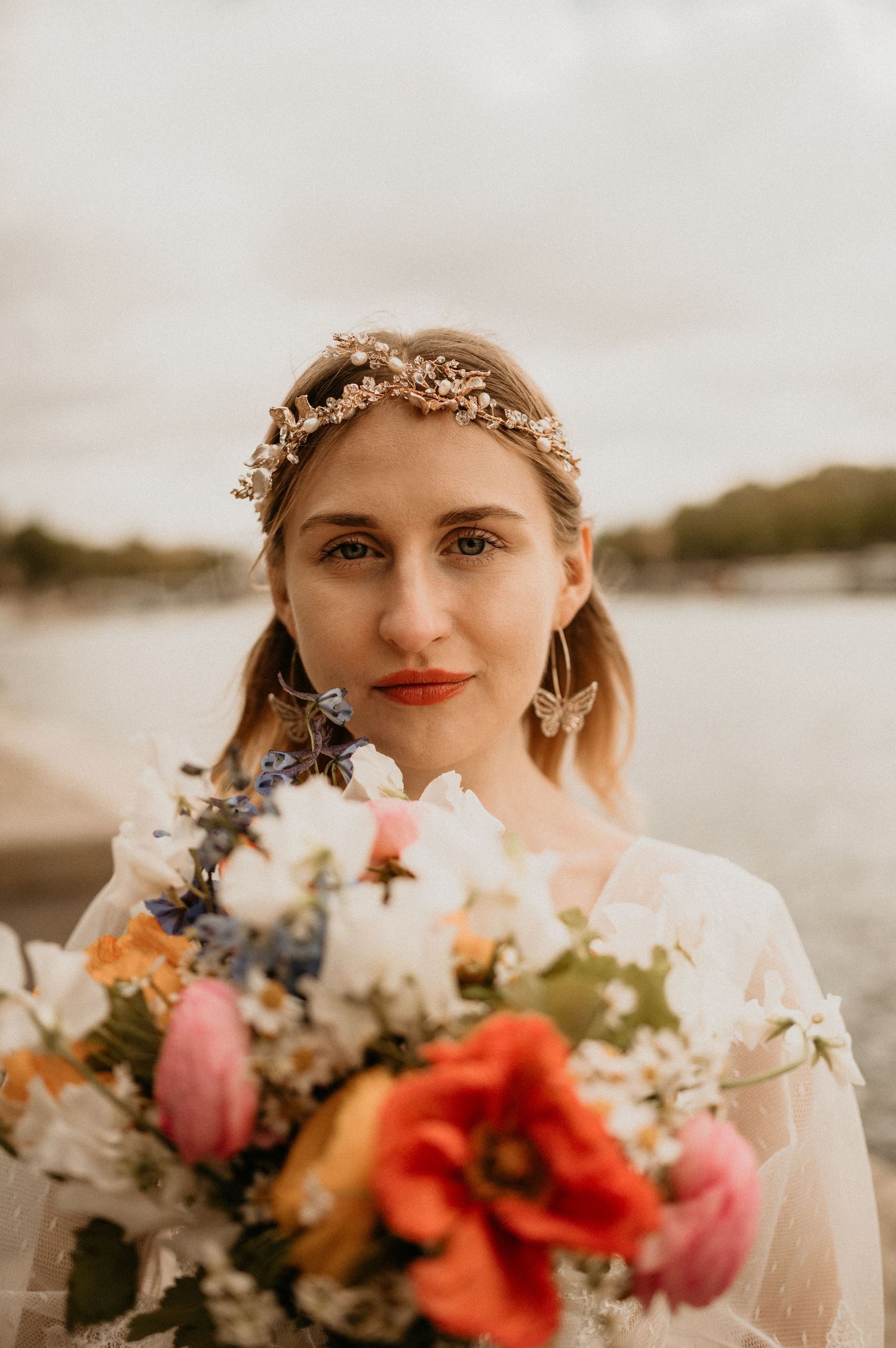 An autumn bridal portrait featuring a flower crown and colorful bouquet by the riverside.
