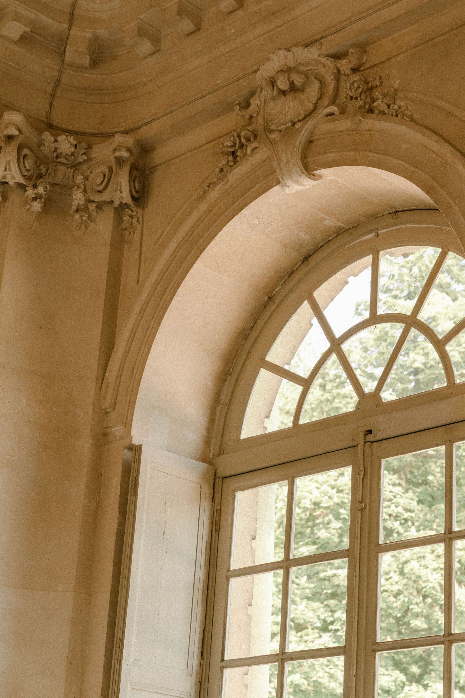 Architectural detail of arched window with ornate molding in French chateau interior.