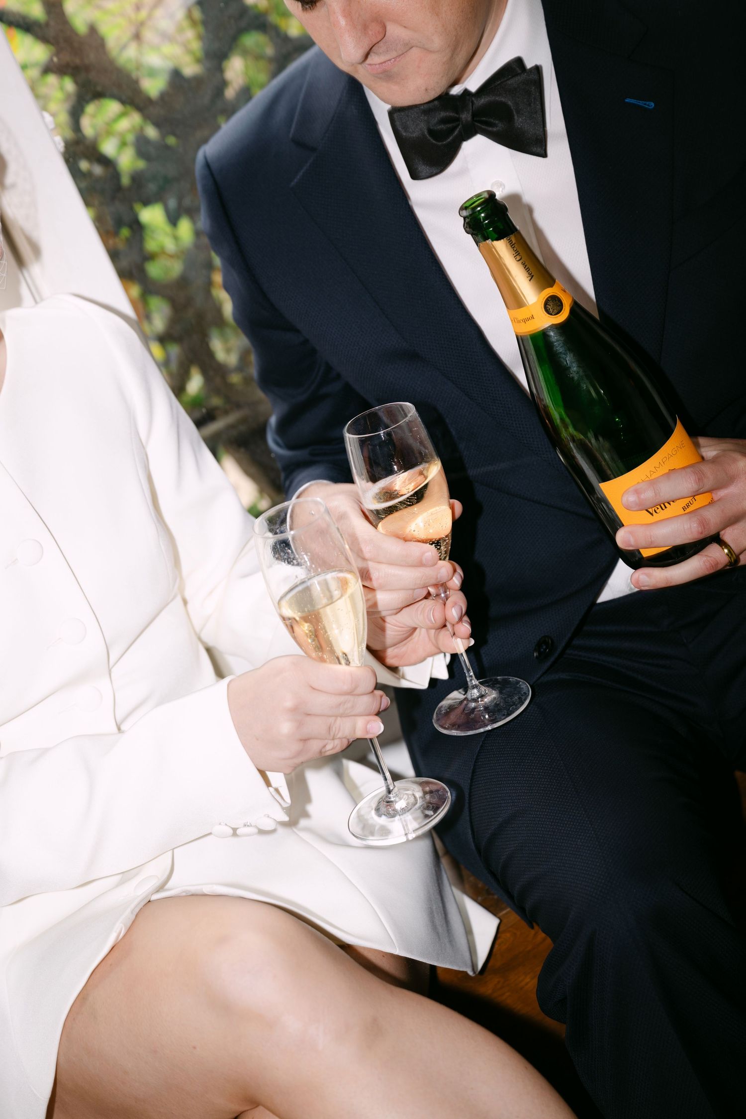 People in formal attire hold champagne glasses while celebrating at an elegant event.