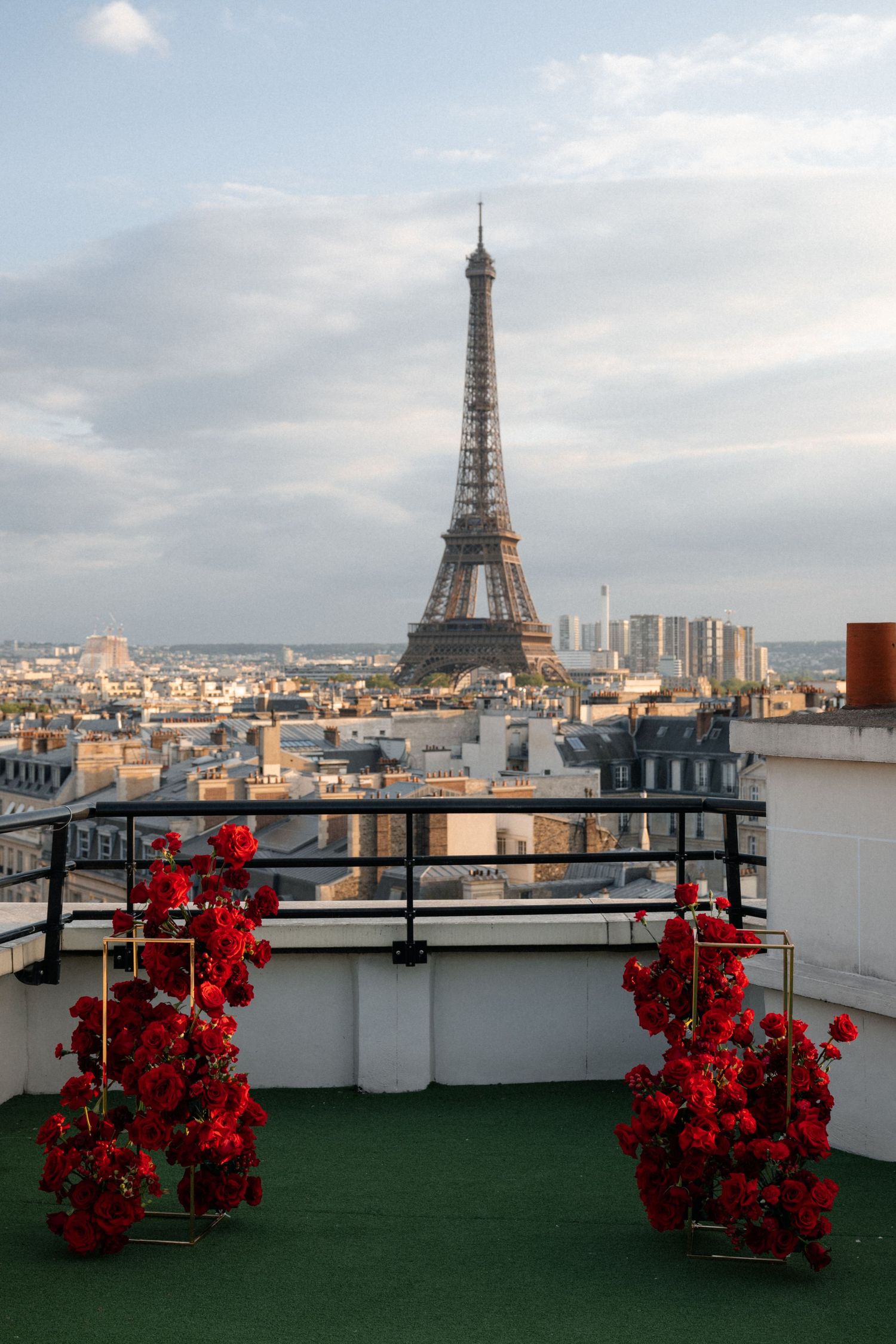 Romantic rooftop wedding ceremony setup with red floral arrangements and iconic Eiffel Tower backdrop in Paris.