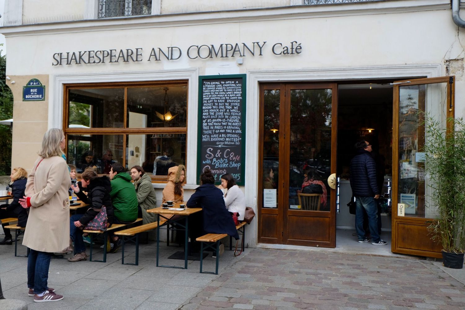 Shakespeare and Company Cafe storefront in Paris with wooden bench seating outdoors.