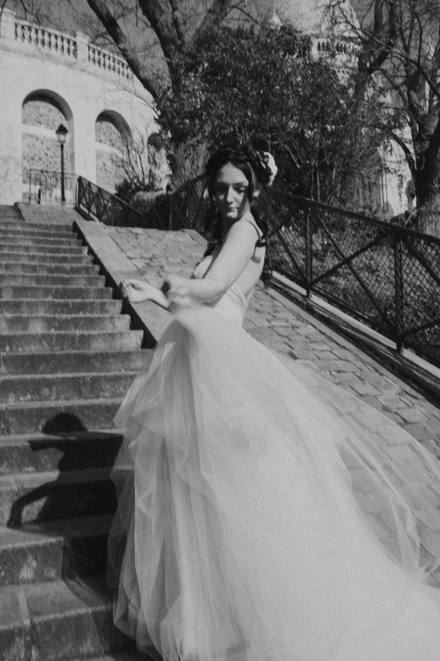 Artistic black and white bridal photo showing movement of dress on grand staircase.