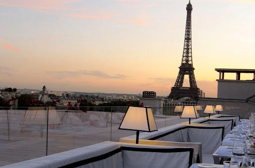 Elegant rooftop terrace with table lamps and Eiffel Tower view at sunset in Paris.
