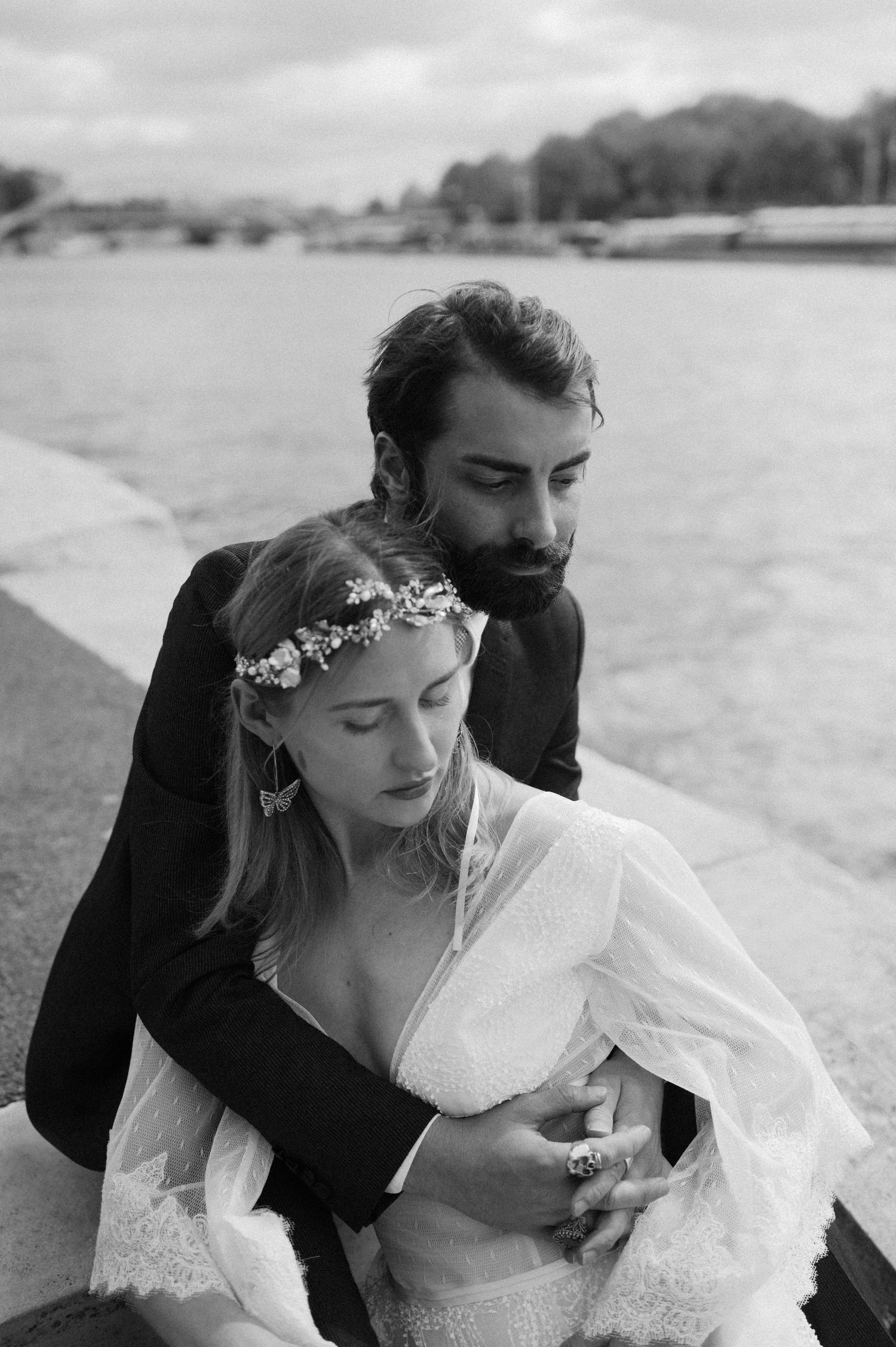 Black and white photograph of embracing newlyweds along the Seine River in Paris.