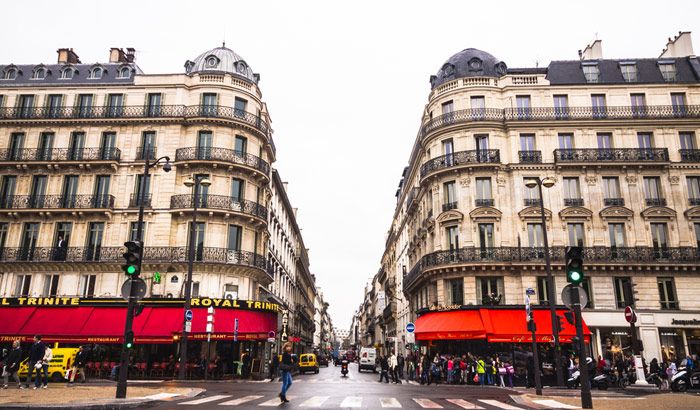 Symmetrical view of classic Parisian buildings converging on a rain-wet street.