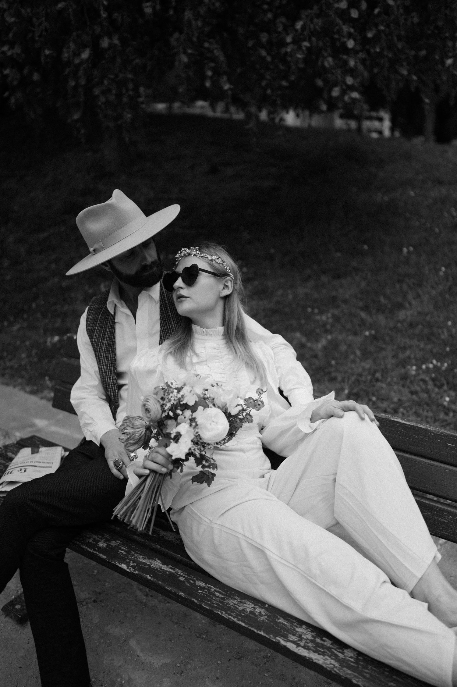 Black and white photo of couple on park bench with vintage styling and flowers.