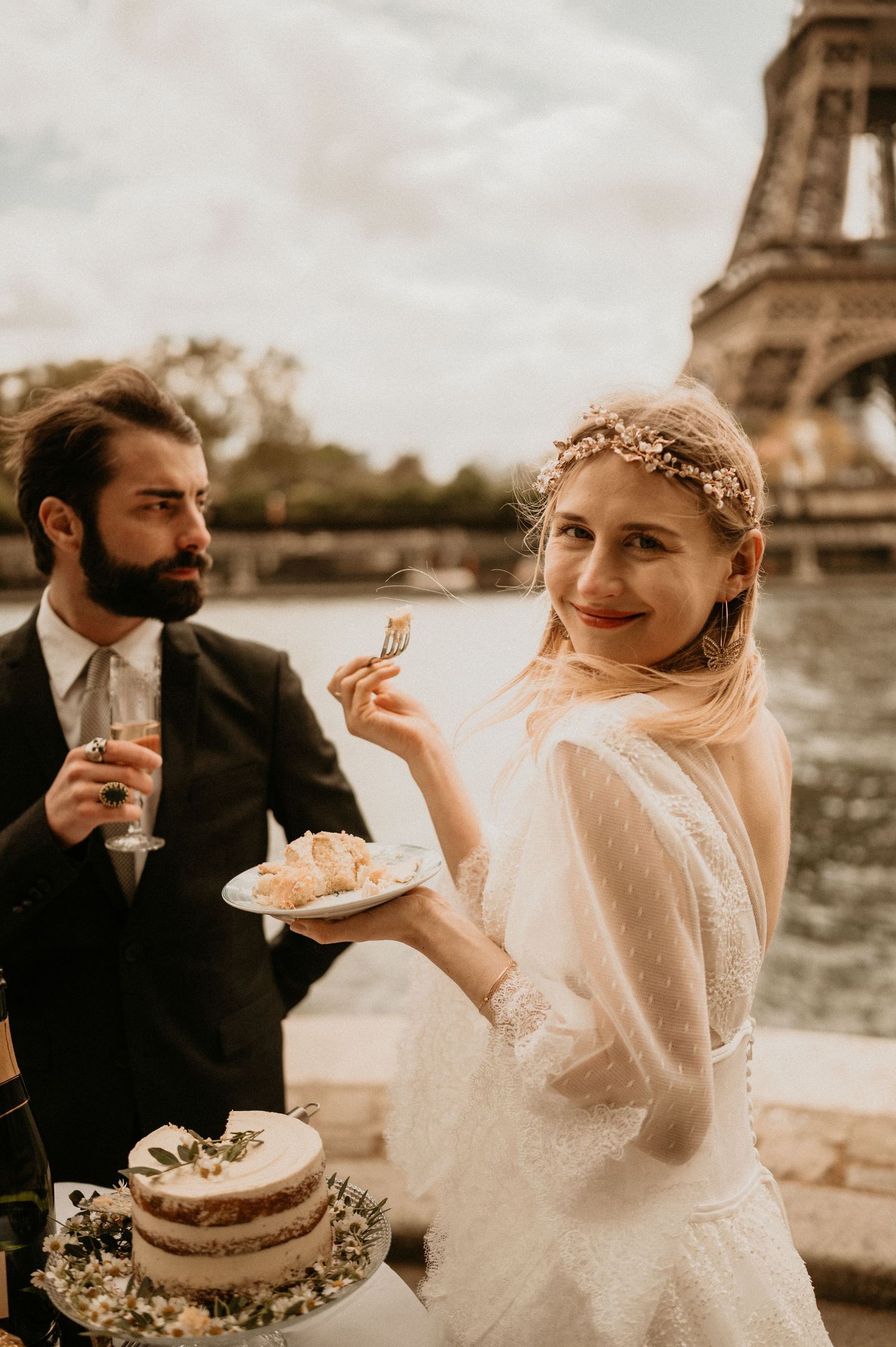 A wedding couple sharing cake by the Eiffel Tower in Paris.