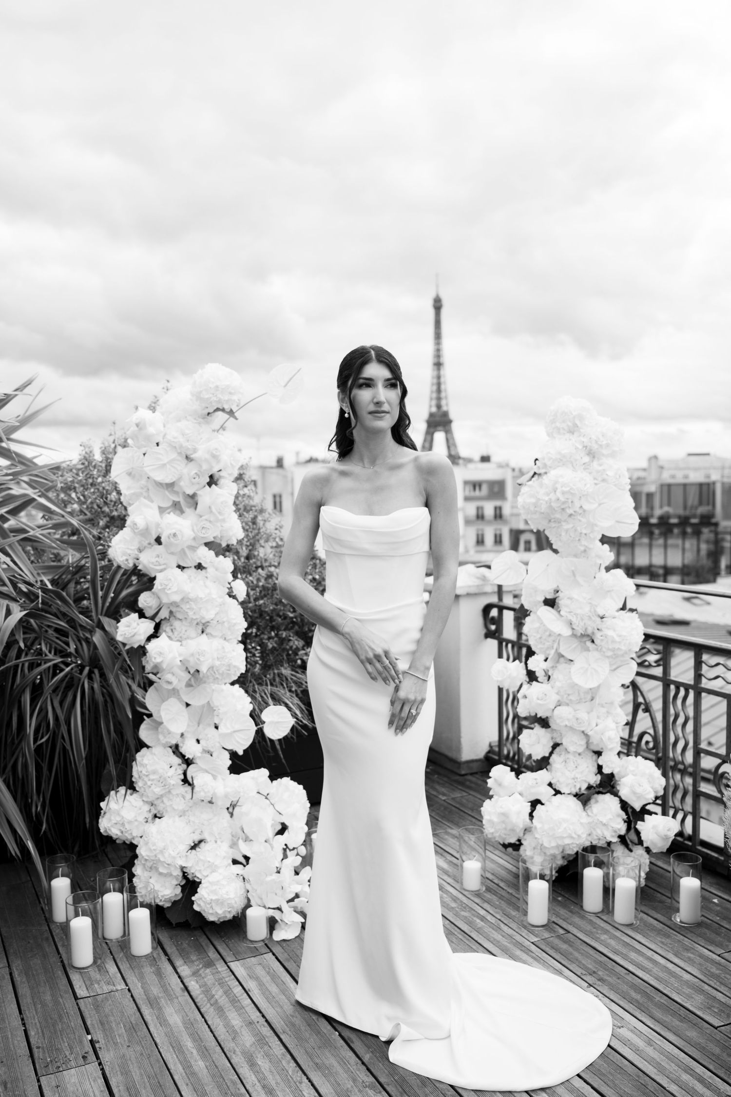 Black and white portrait of bride in strapless gown on Paris rooftop with Eiffel Tower backdrop.