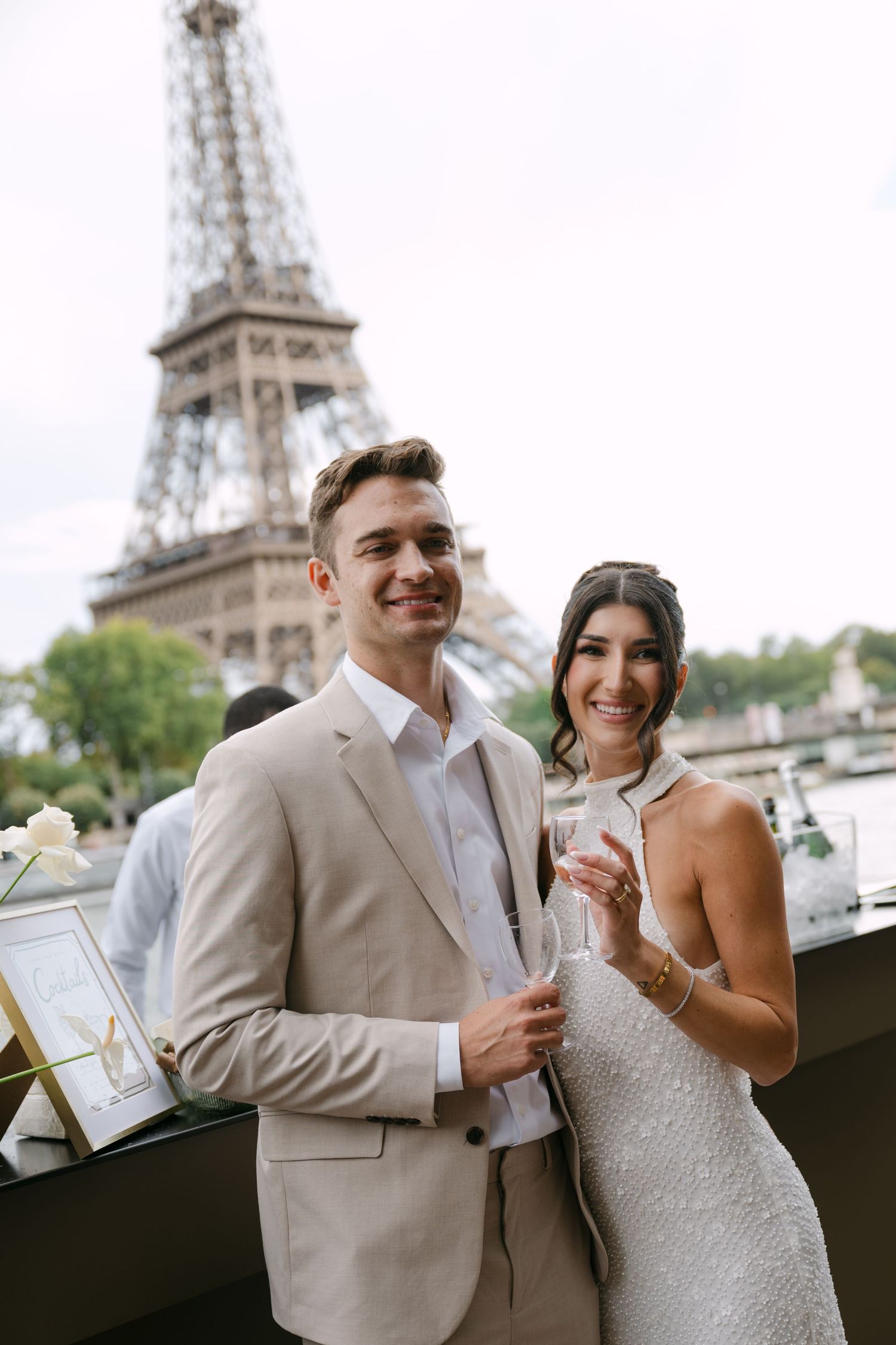 A couple celebrates with champagne on a balcony overlooking the iconic Eiffel Tower in Paris.