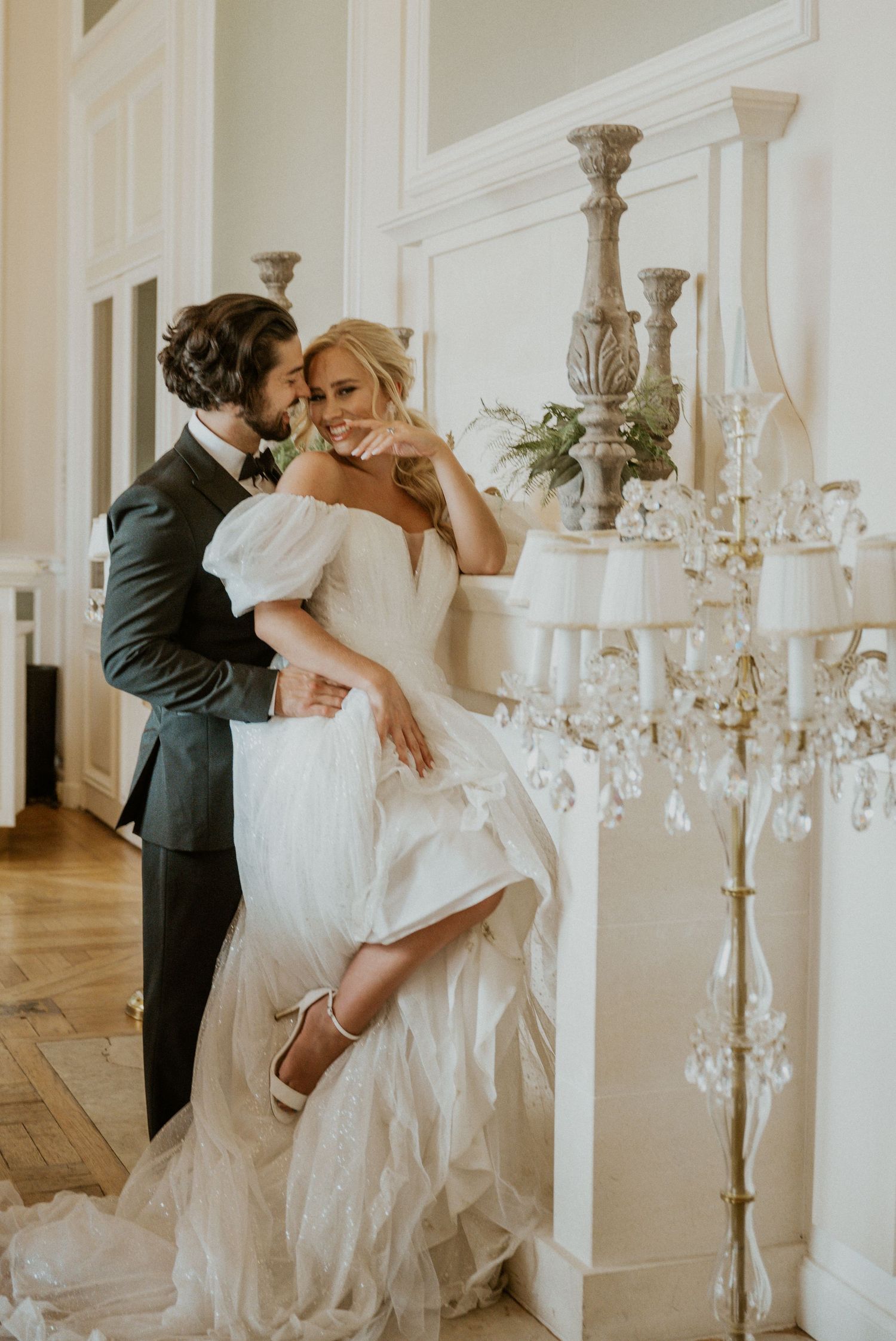 Intimate wedding couple moment in elegant interior with crystal chandelier.