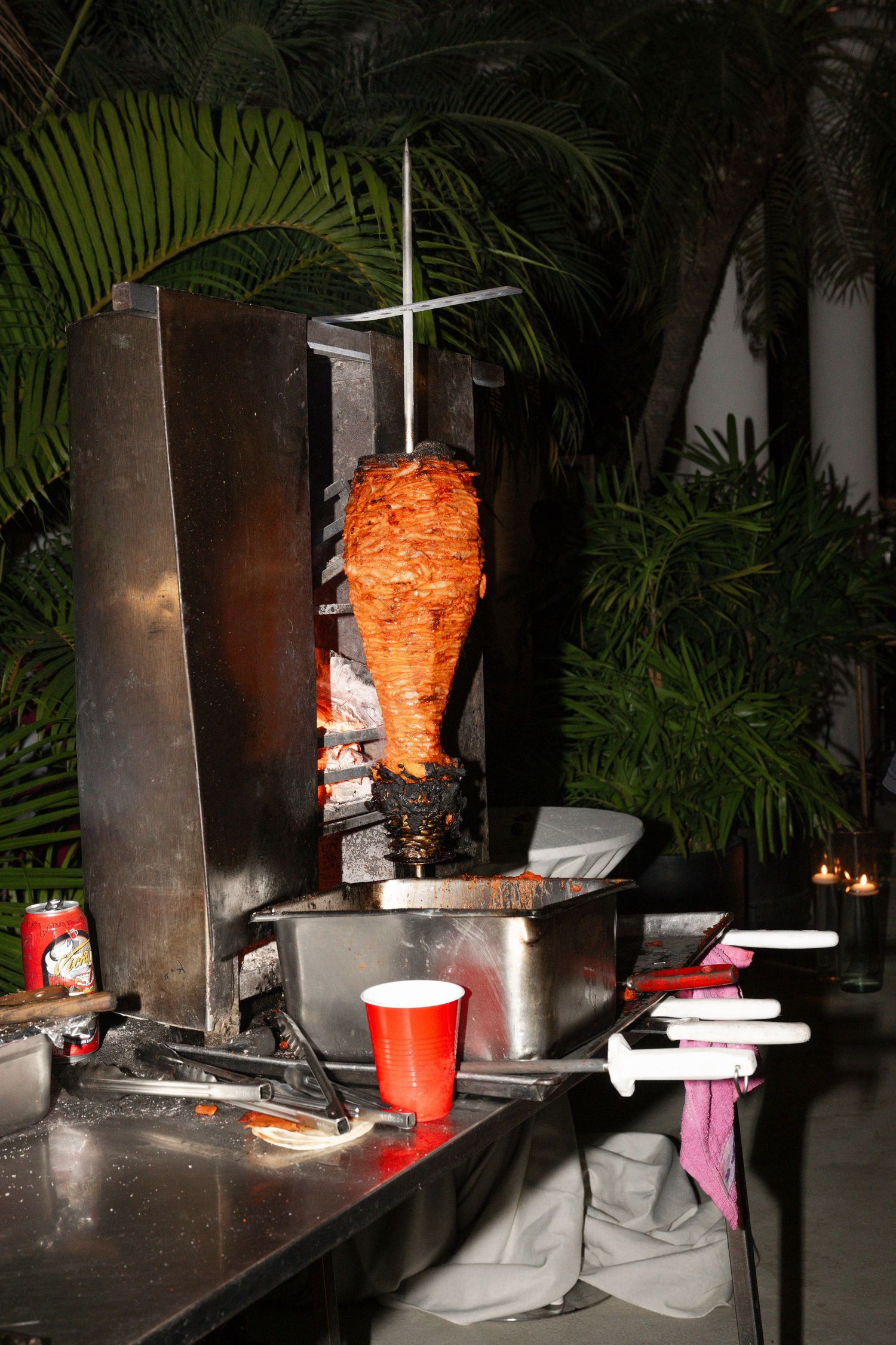 Rotating spit of shawarma meat cooking at outdoor wedding reception food station.