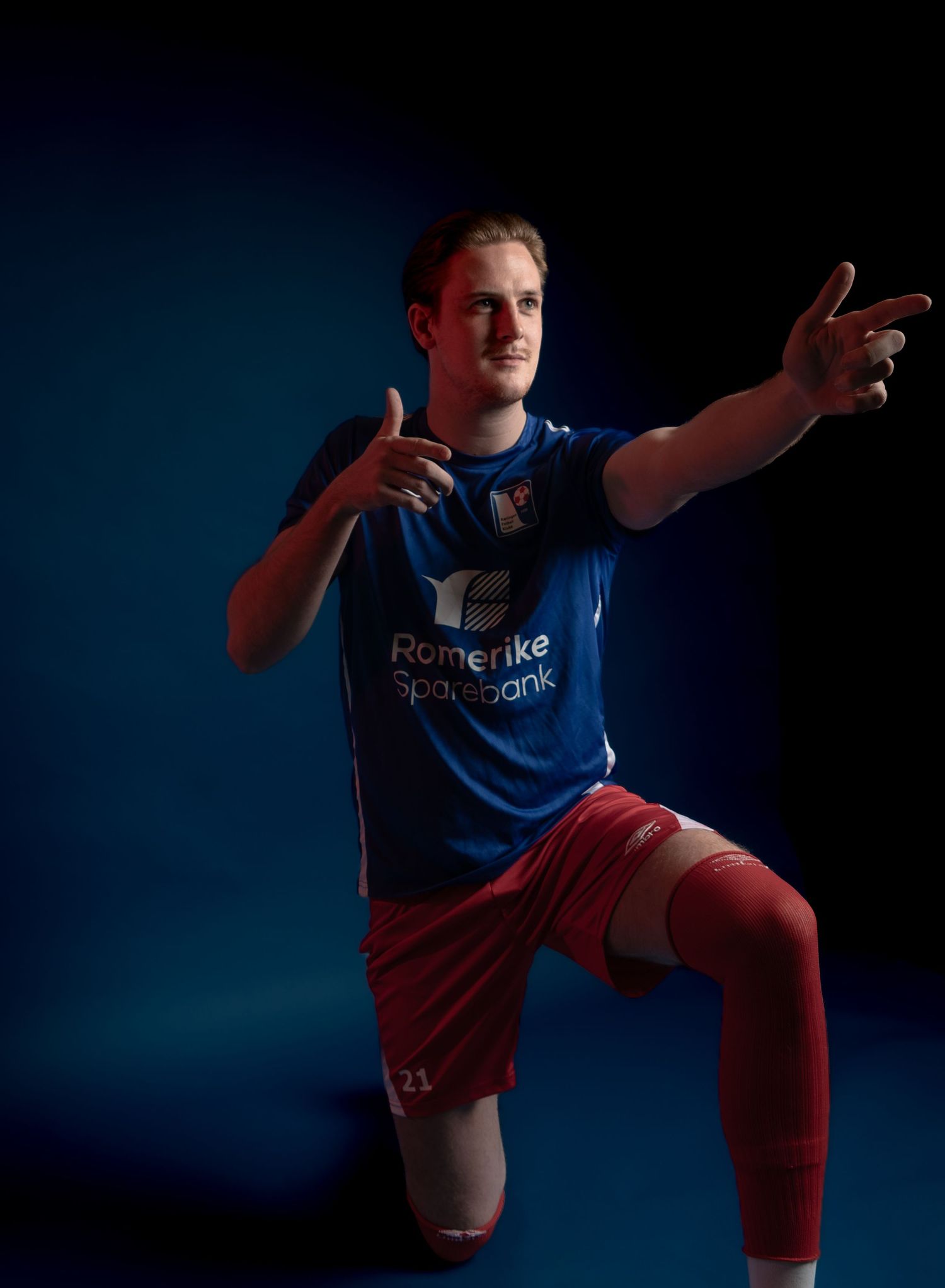 Athletic figure in blue and red uniform demonstrates dynamic kicking motion in studio.