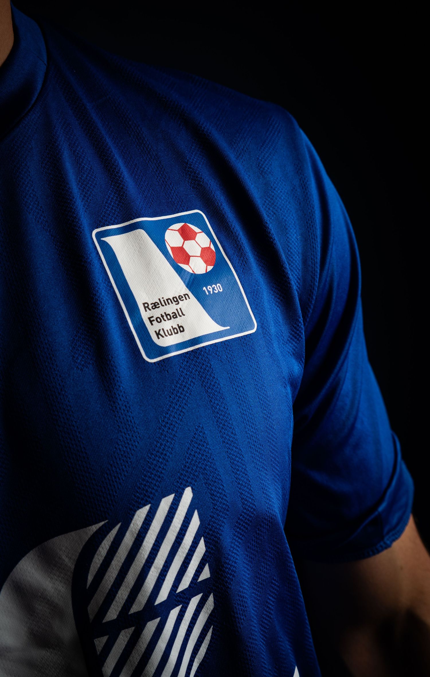 Detail shot of blue soccer uniform with white club logo and striped design.