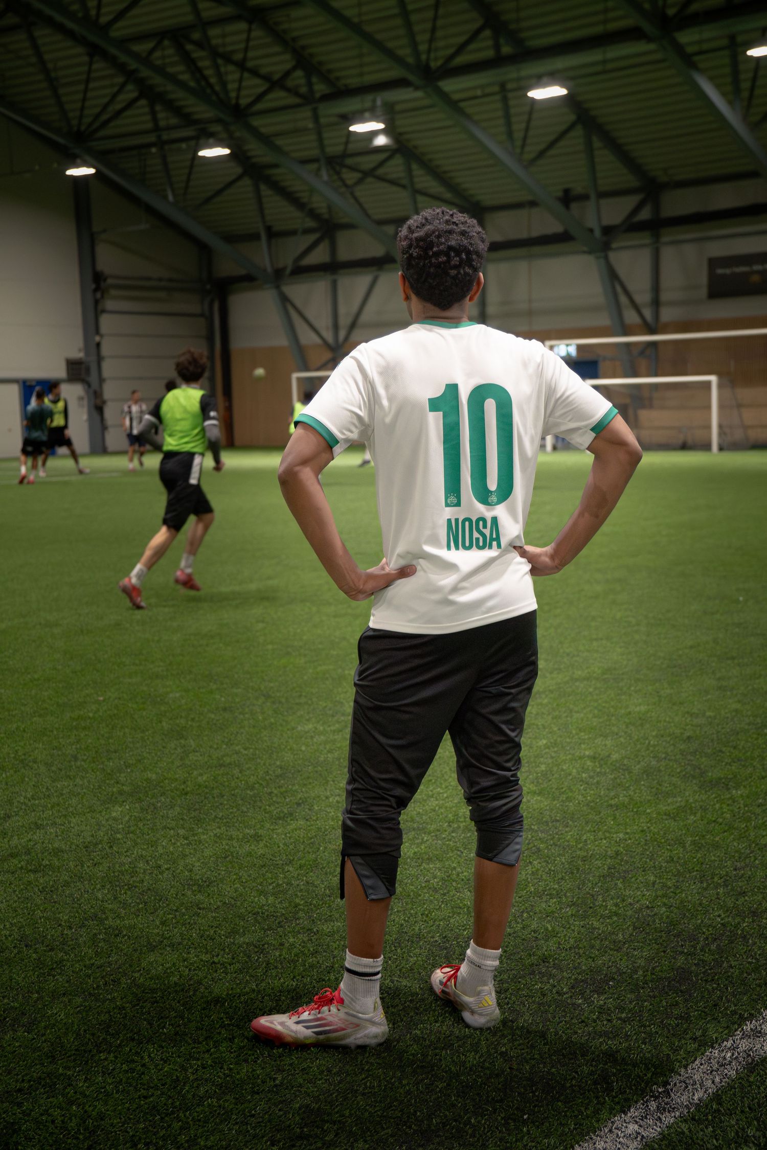 Soccer players lined up on indoor turf field wearing white jerseys with number 10.