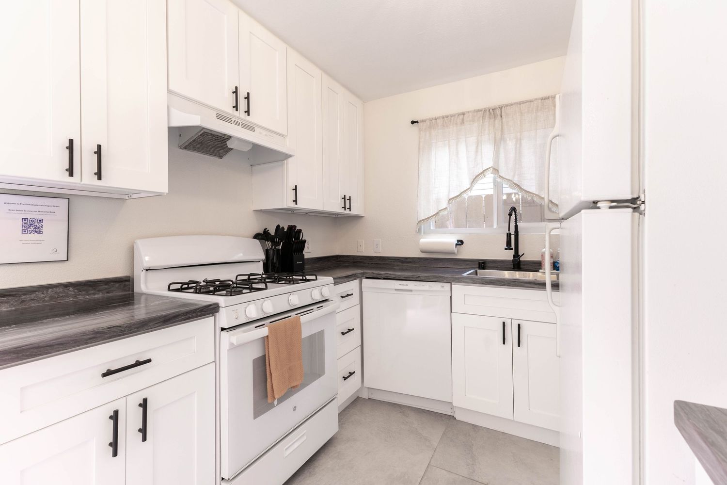White kitchen with gas stove, dark countertops, and classic cabinetry.