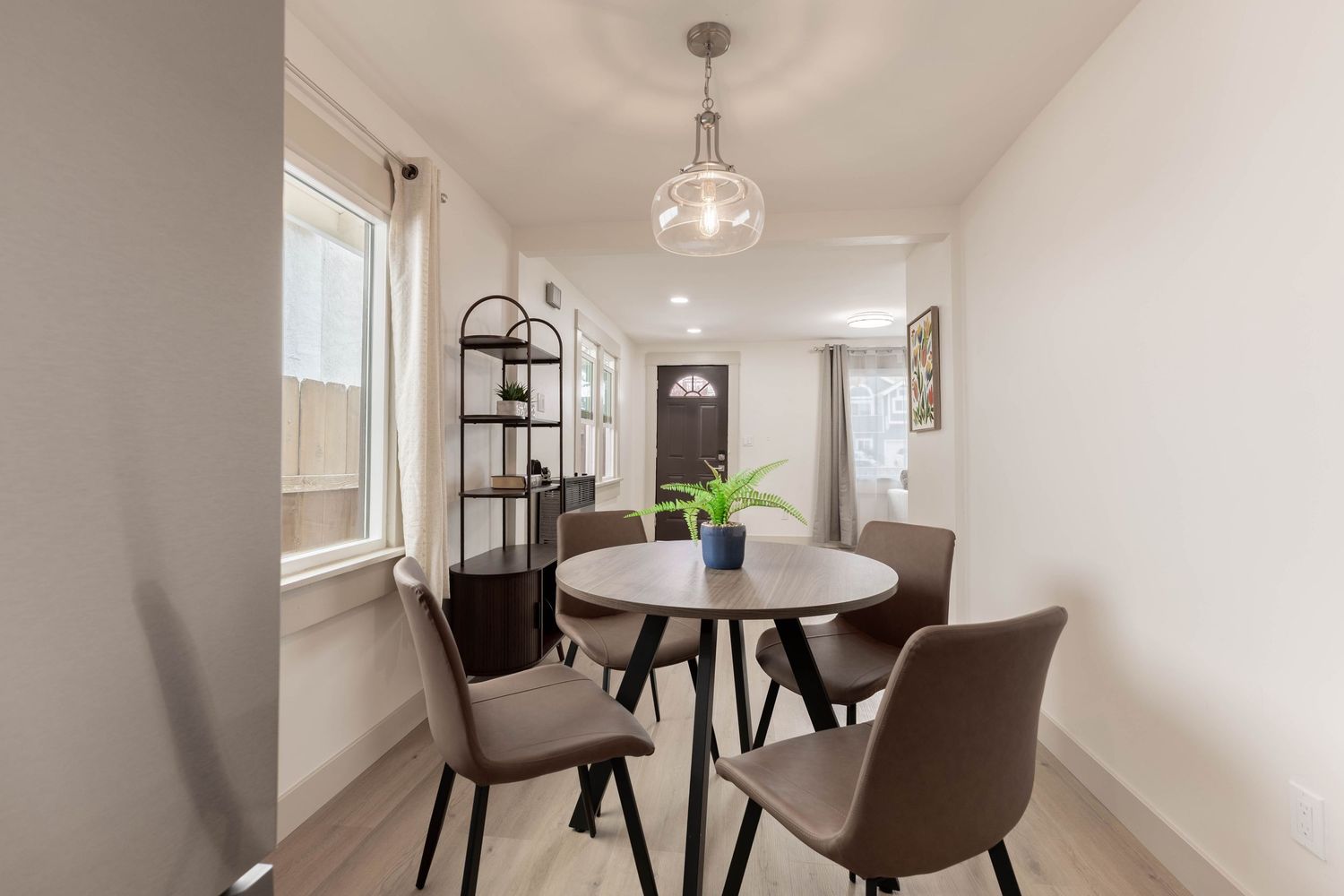 Modern dining area with round table, brown chairs, and pendant light.