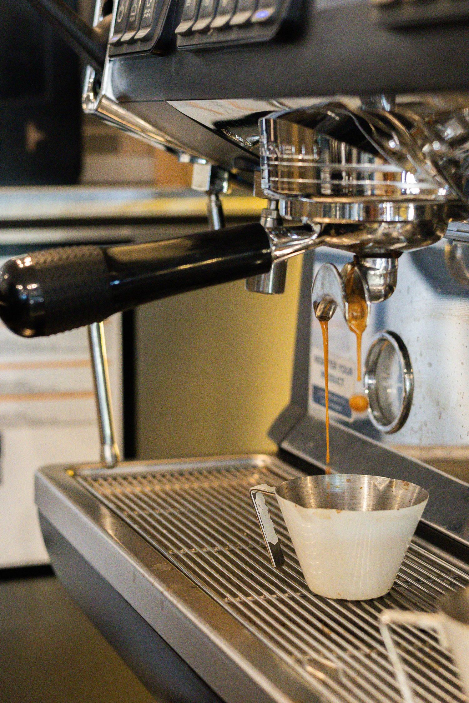 A professional espresso machine pouring fresh espresso shots into a small cup in a modern cafe.