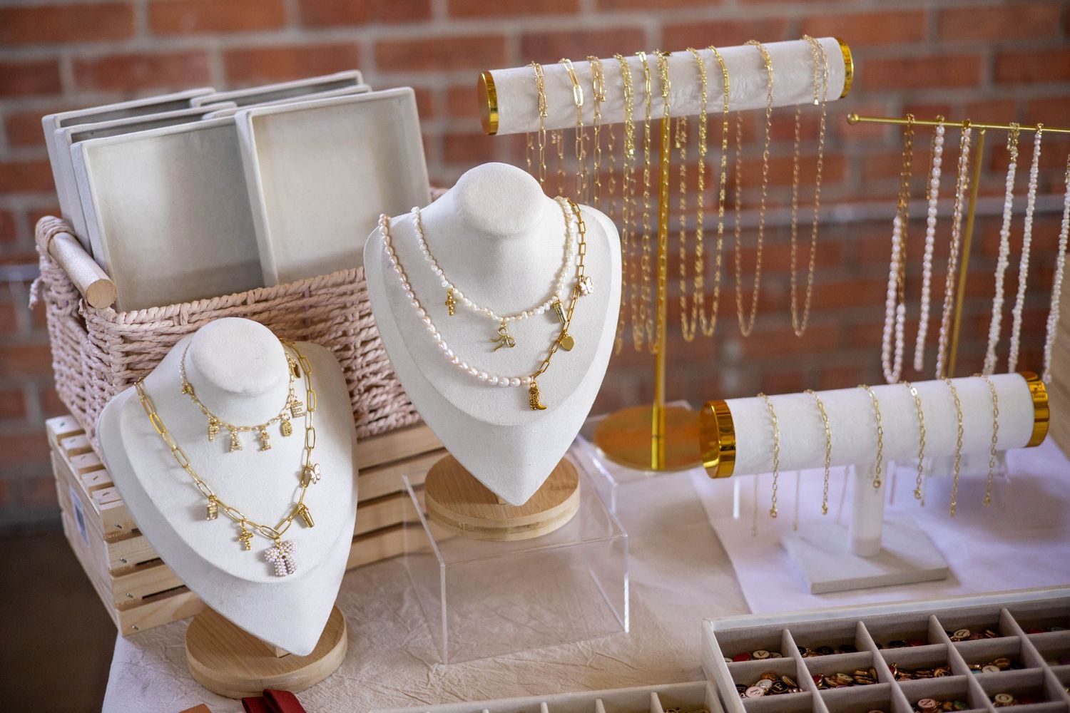 Gold and pearl jewelry display with necklaces on white bust stands and tiered holders at a boutique jewelry sale.