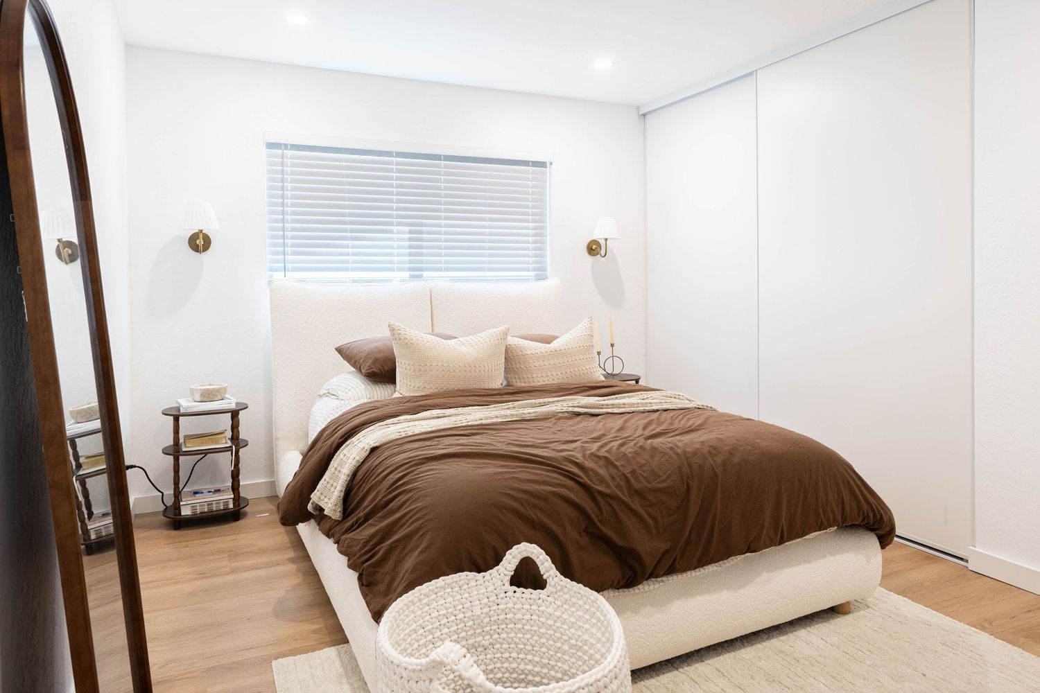 Modern bedroom with brown duvet, white wardrobe, timber floors, and neutral tones in a minimalist design.