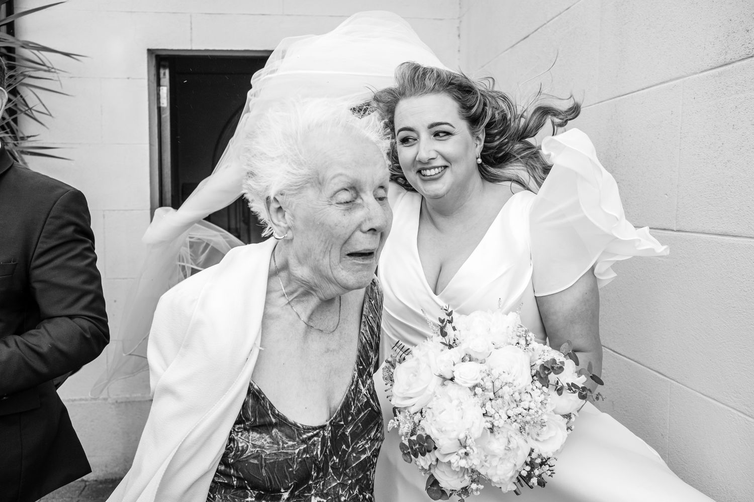 Wedding party members share joyful laughter during formal photos.