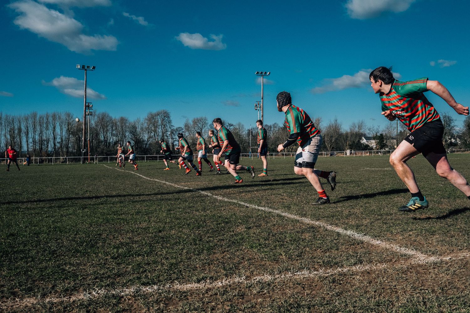 Athletes running on a sports field during a competitive event under bright blue skies.