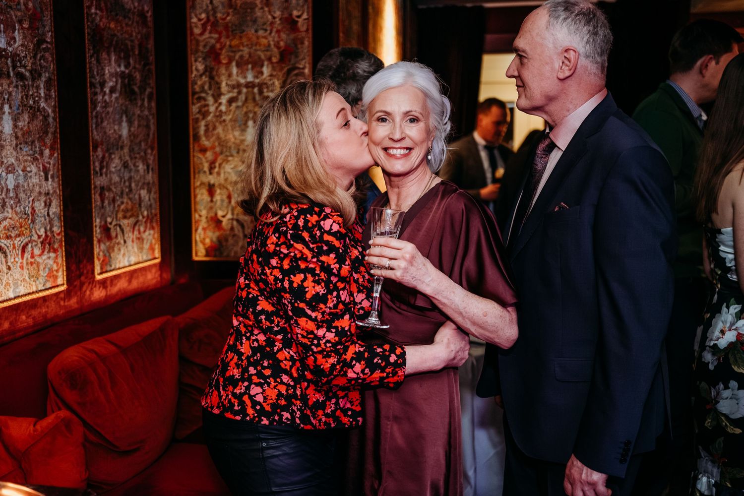 A warm gathering of friends enjoying drinks in a cozy bar with red ambient lighting.