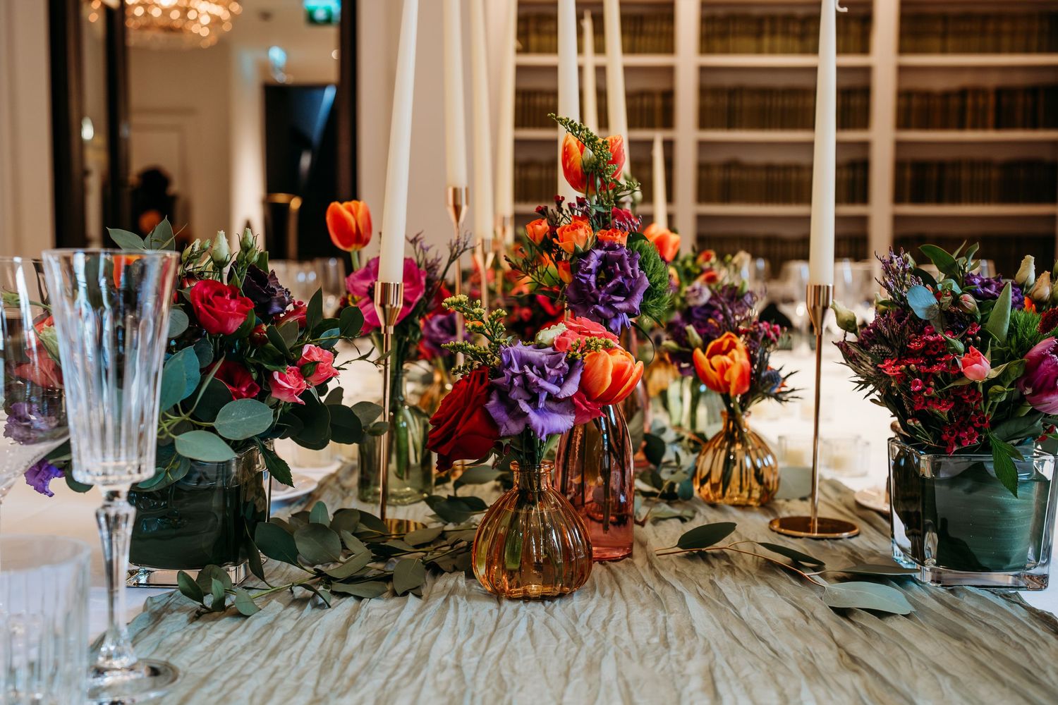 Elegant table setting with colorful floral centerpieces and glassware for a formal dinner.
