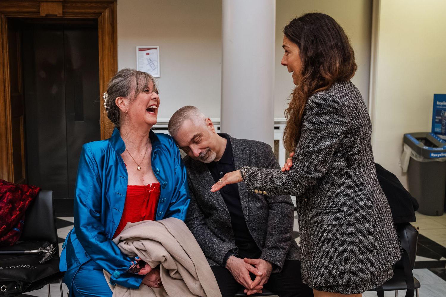 Three people sharing a lighthearted moment in casual indoor setting.