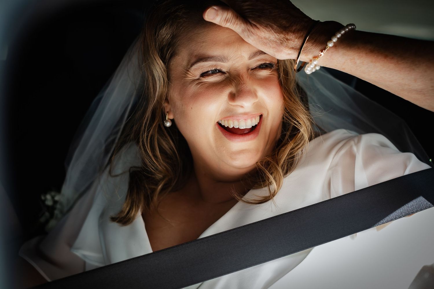 Joyful expression captured through car window on wedding day.