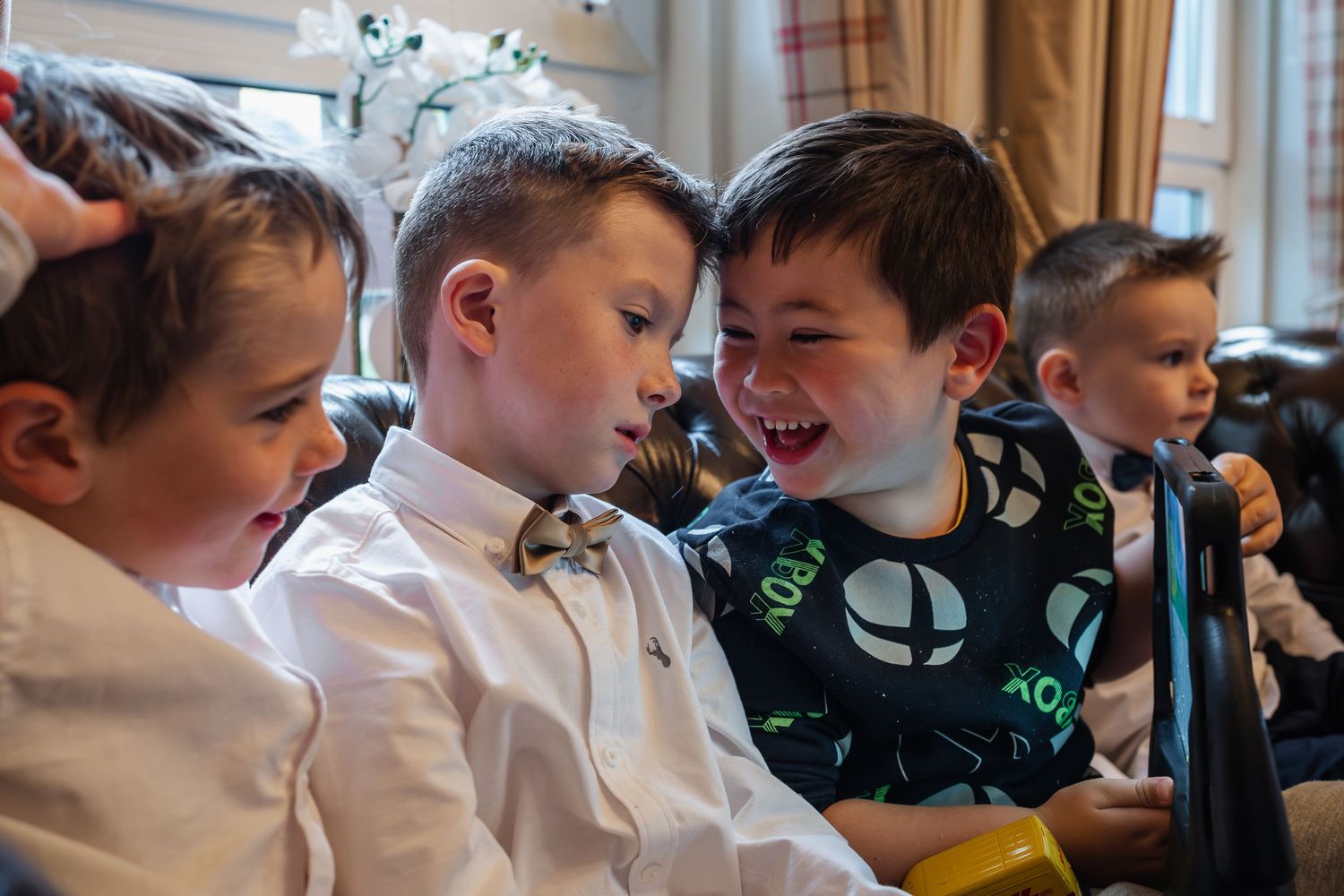 Joyful young boys in formal attire laughing and playing together at a wedding reception.
