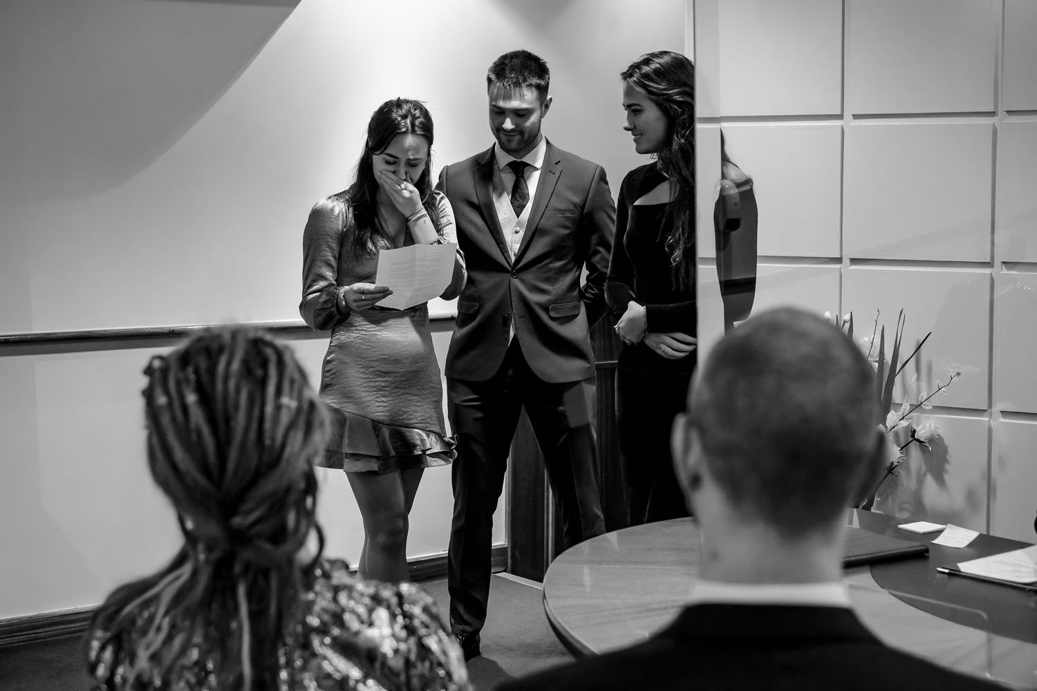 Black and white photo of business professionals reviewing documents in a modern office meeting room.