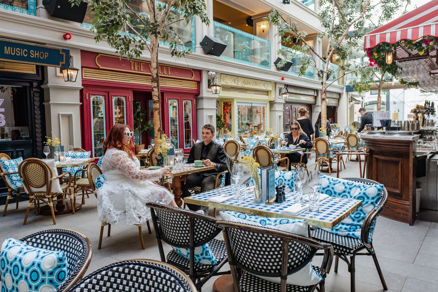 Outdoor cafe scene with blue and white bistro chairs and table settings on charming street.