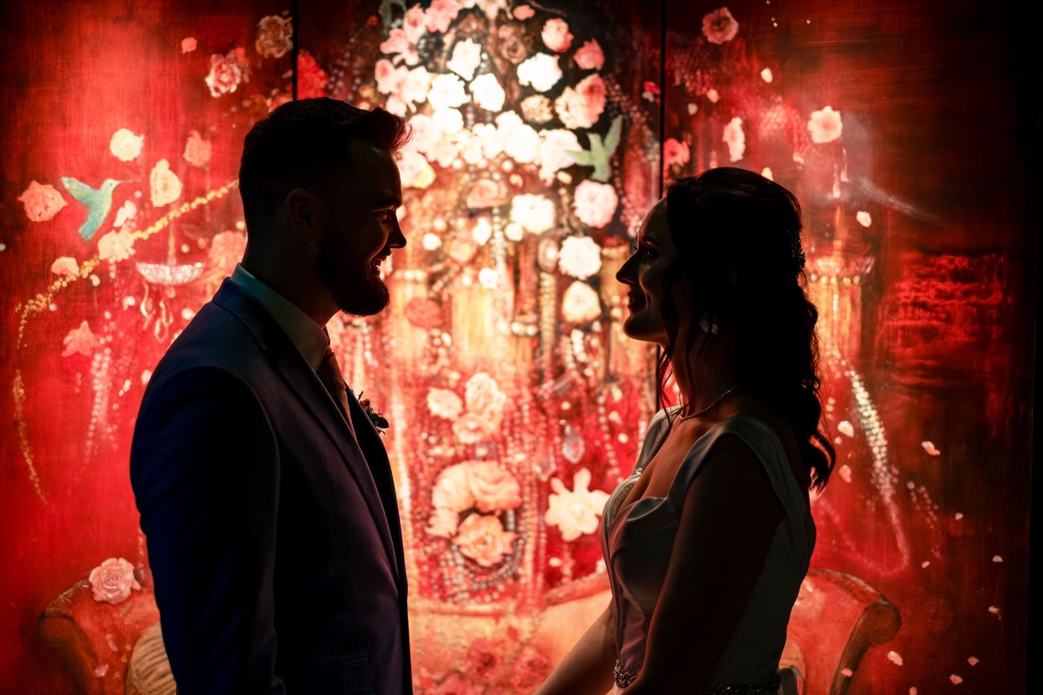 Silhouetted couple against red glowing backdrop with floating lights.