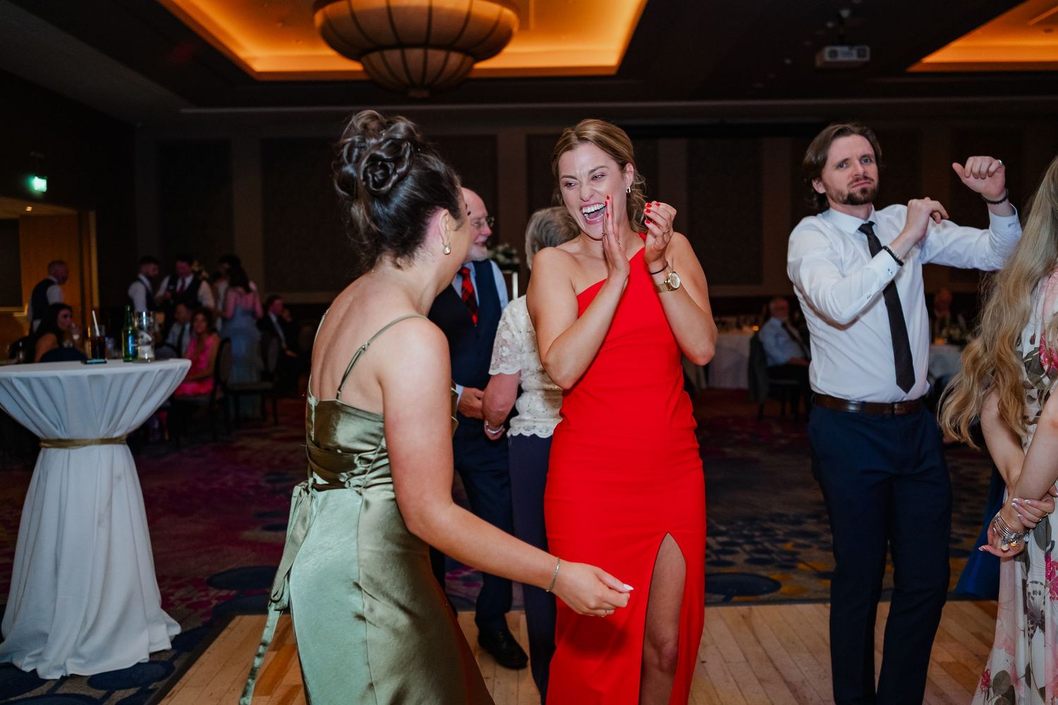 People enjoying themselves on a dance floor at an indoor event with amber lighting.