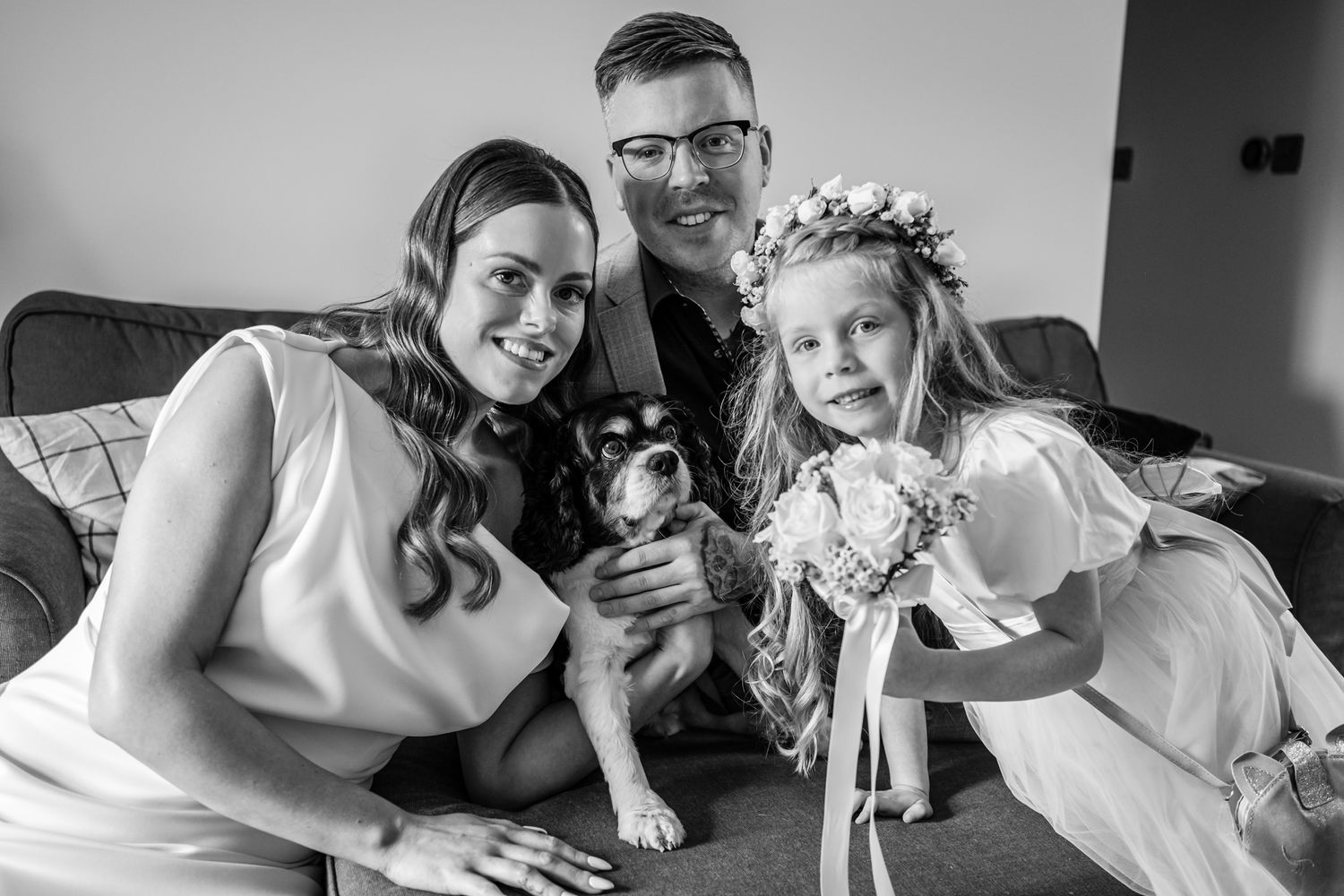 Family portrait on couch with small dog wearing matching outfits in black and white.
