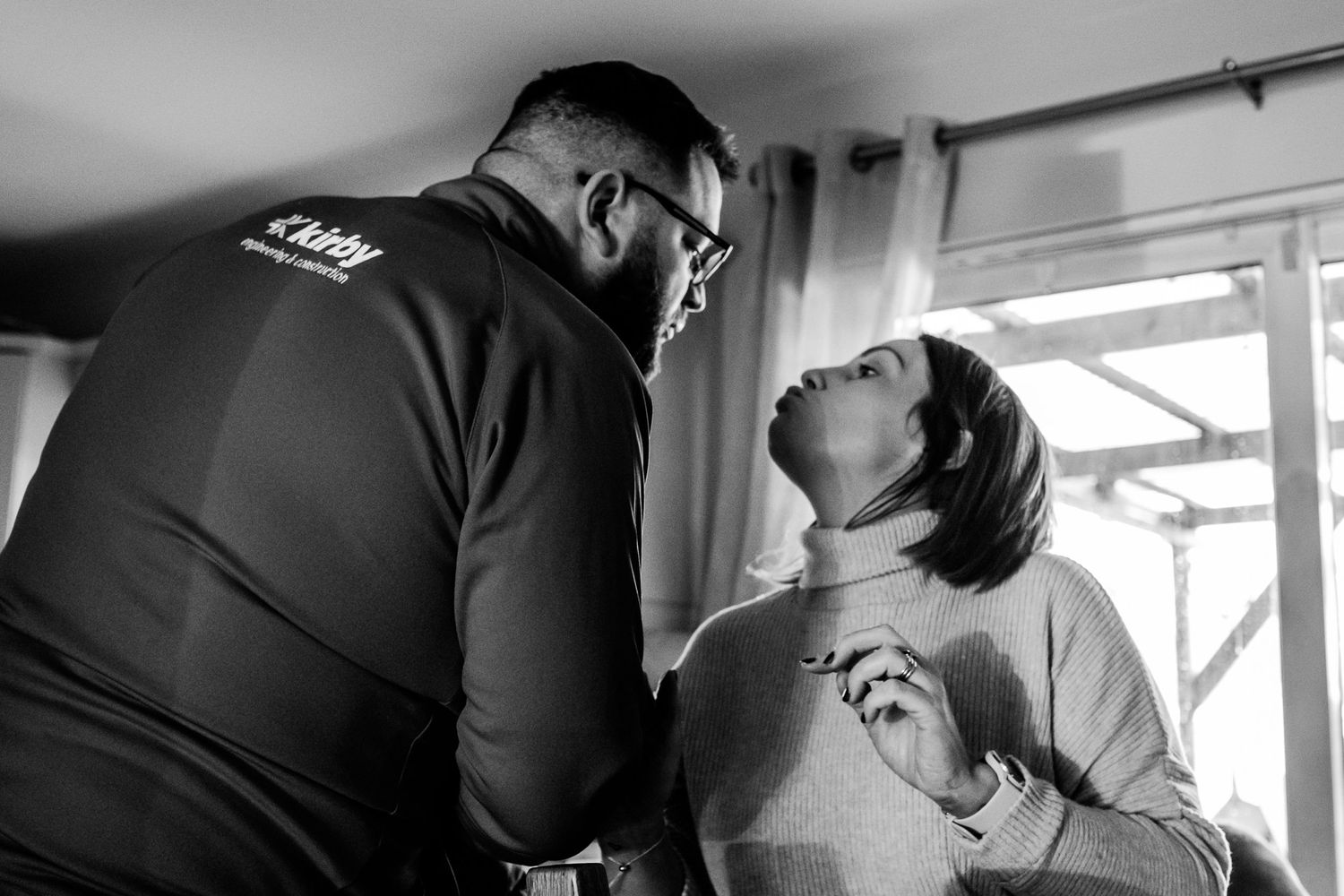 Black and white candid moment between two people indoors.