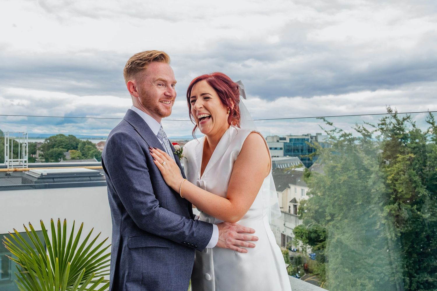 Happy couple sharing intimate moment on balcony with waterfront view.