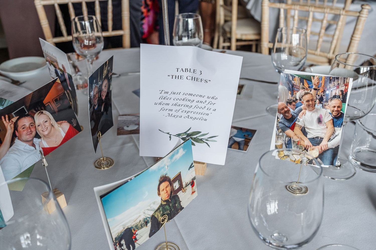 Wedding table display with personalized photo cards, table number sign, and elegant glassware at a reception venue.