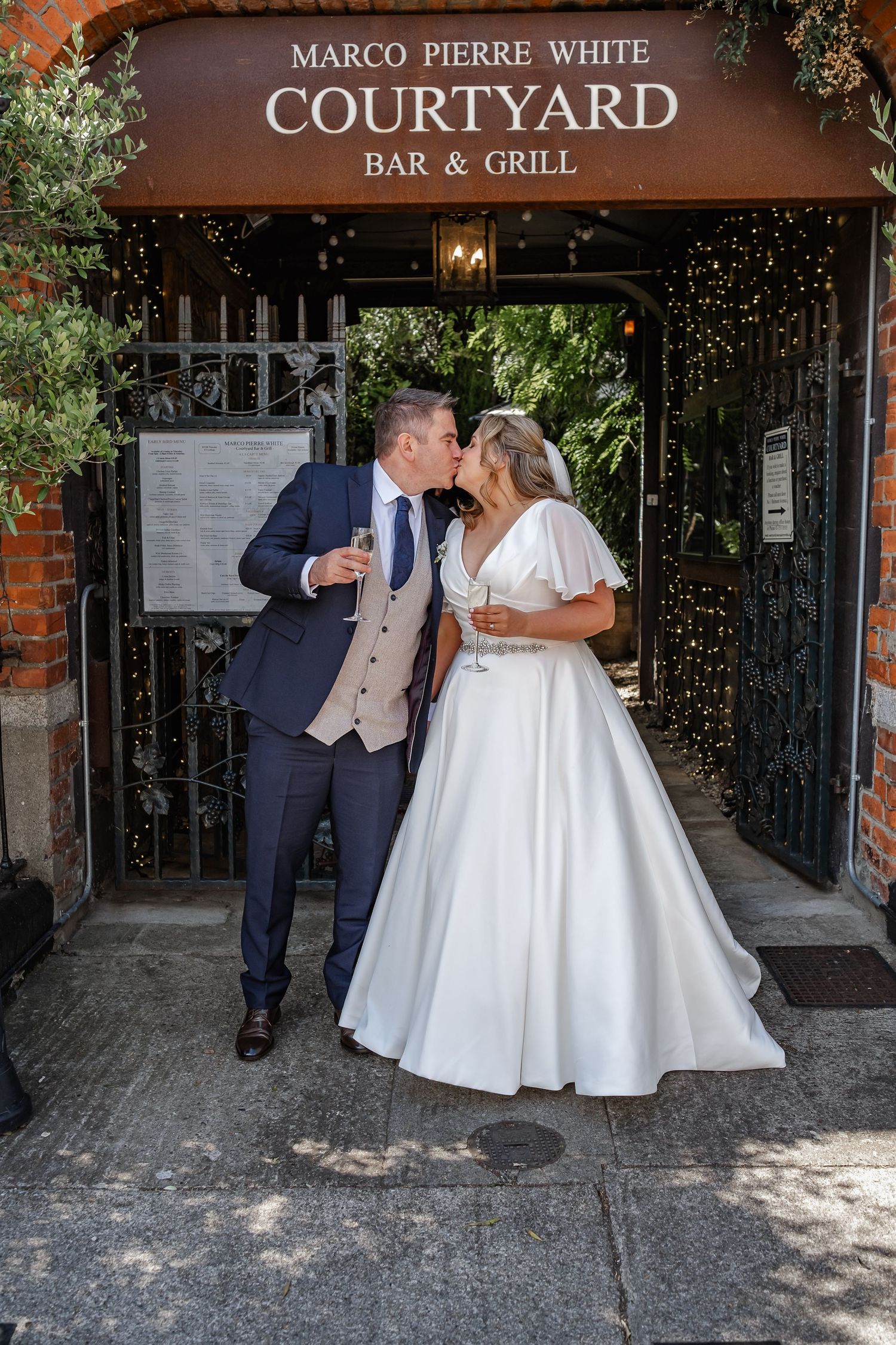 Newlyweds share a romantic moment at the entrance of Marco Pierre White Courtyard Bar & Grill.