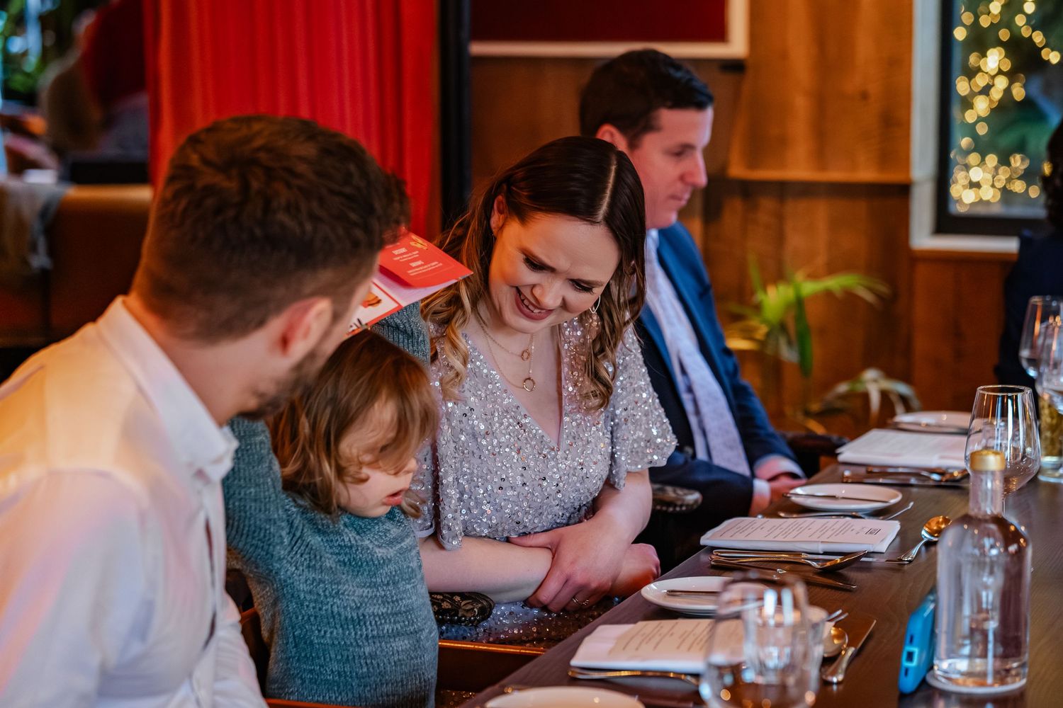 Family and guests gathered around a long dining table at an elegant restaurant dinner event, sharing a warm moment together.