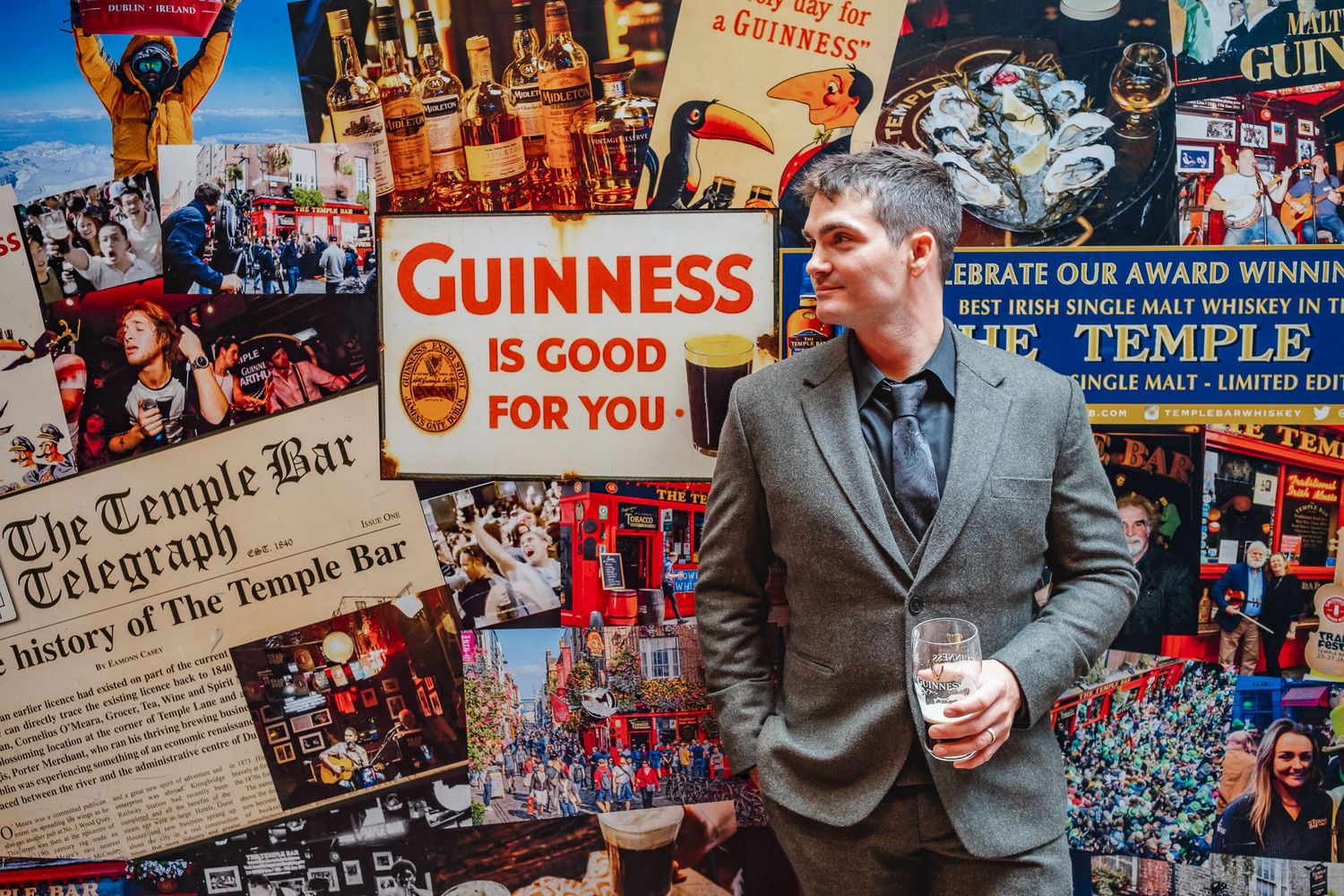A person poses against a wall of vintage Guinness advertisements and newspaper clippings.