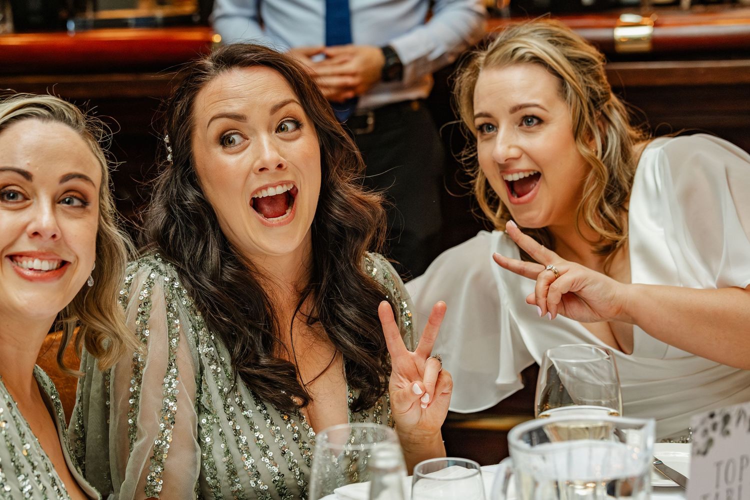 Three wedding guests sharing an excited moment during reception dinner celebrations.