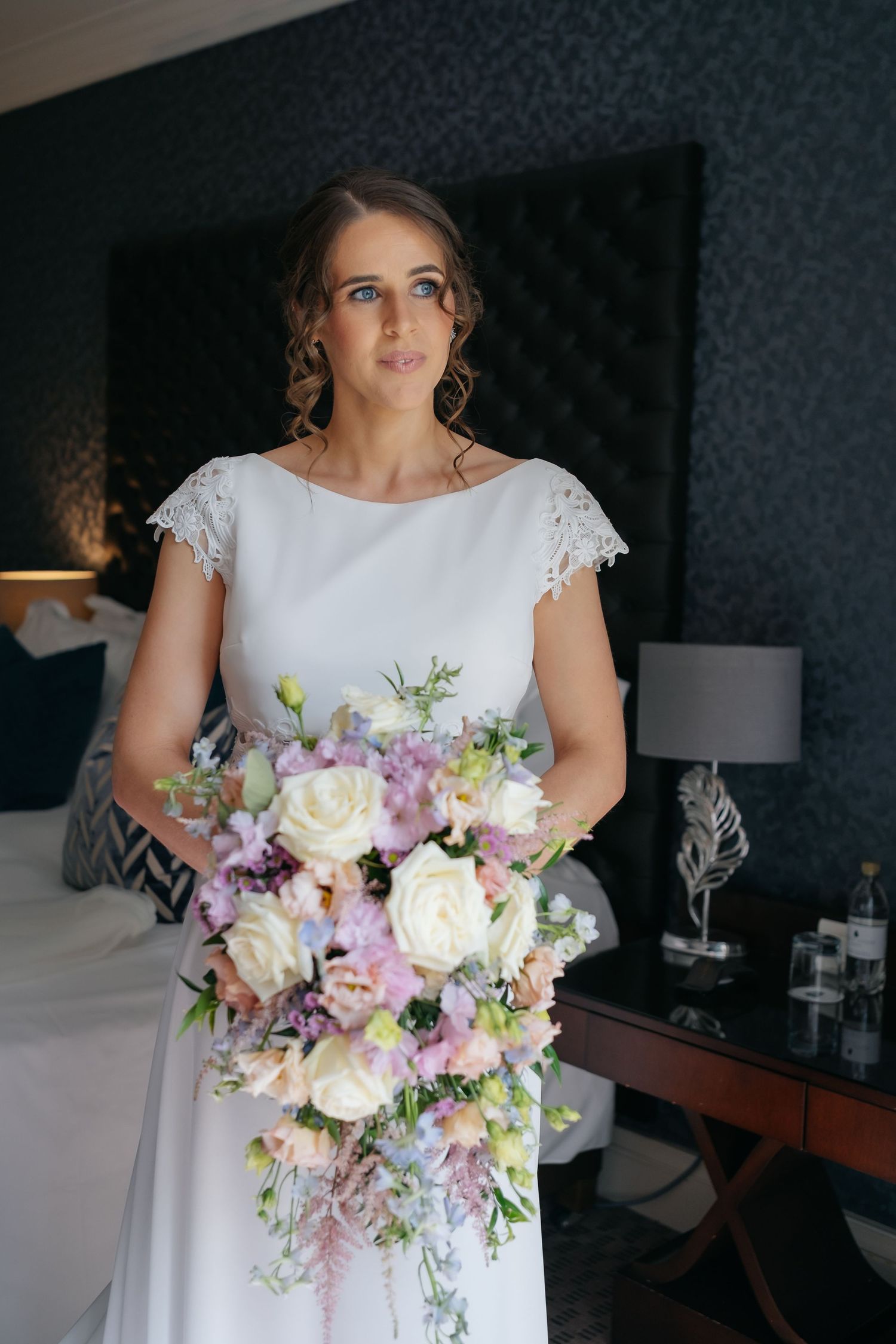 Beautiful wedding bouquet with pink and white roses and lilac flowers held by someone wearing a white lace gown.